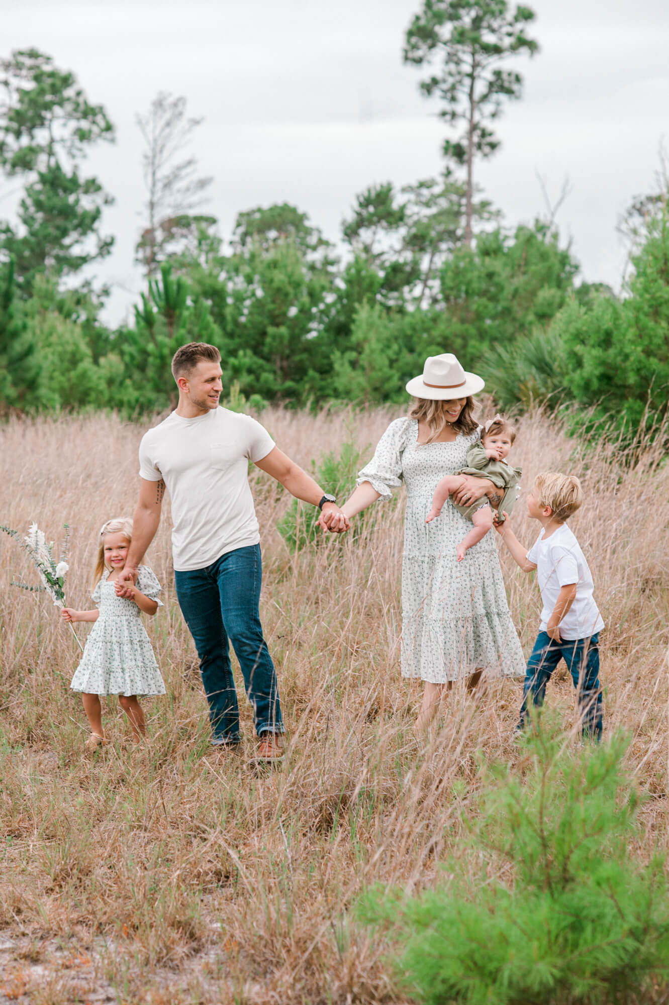 Dr. Keith Hurley the owner of Coastline Family Chiropractic, walking with his family through a field holding hands.