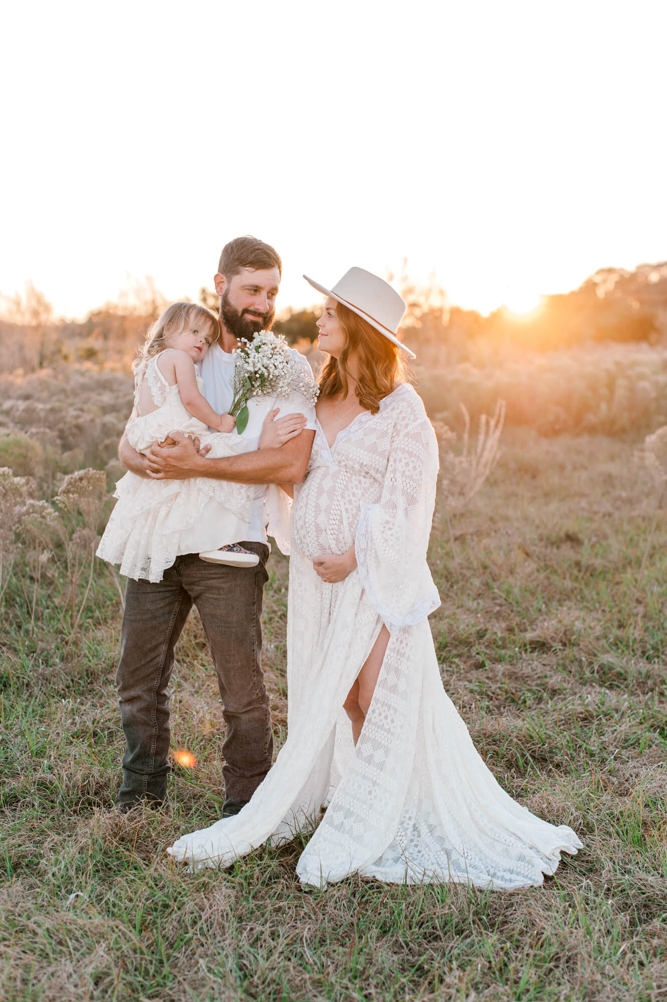 Expectant Mom stands in  field with husband and daughter. Contact Space Coast Doula for all birthing and pregnancy needs. 