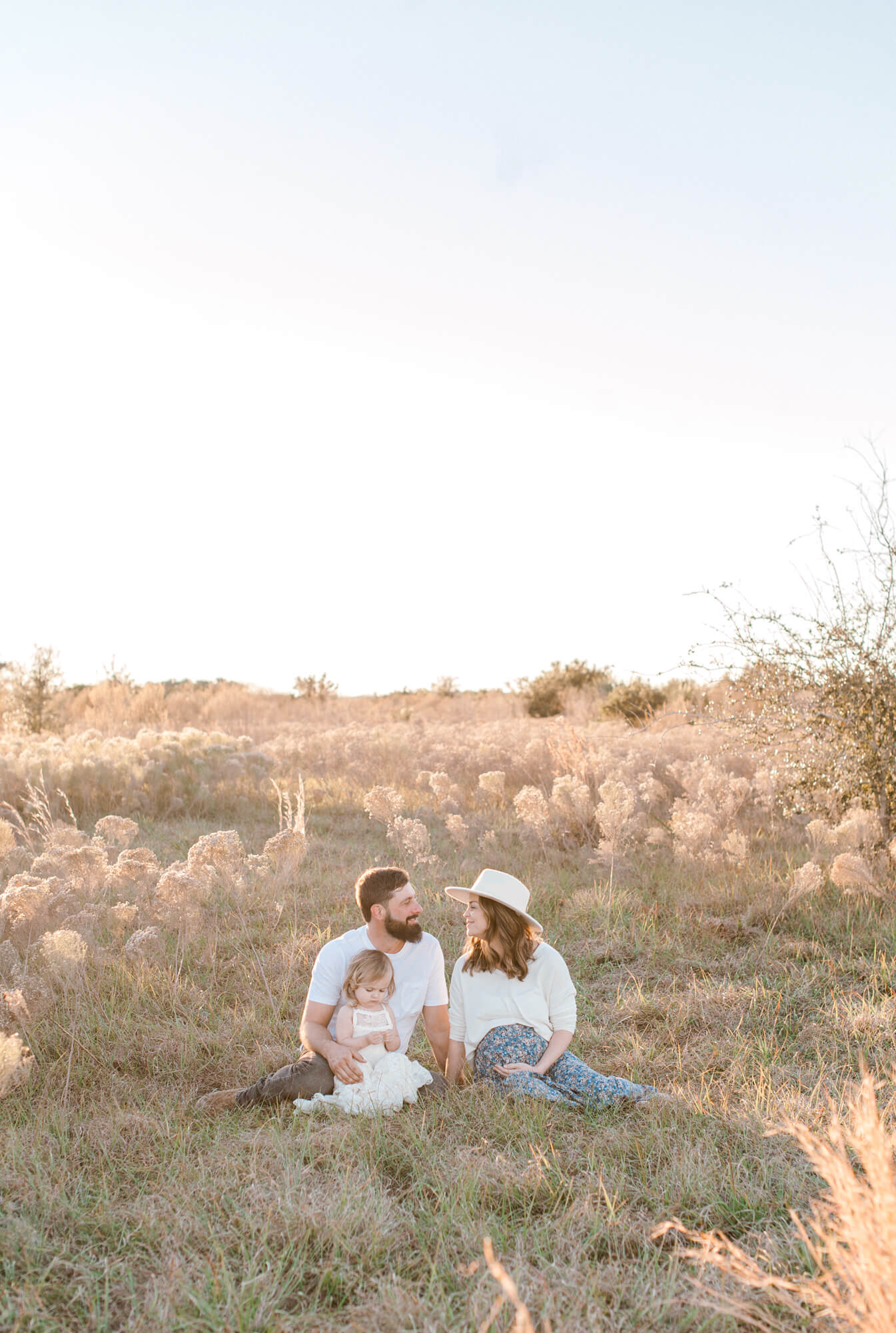 Stunning photo showcasing the beautiful backdrop with the family sitting in a field of tall grass. 