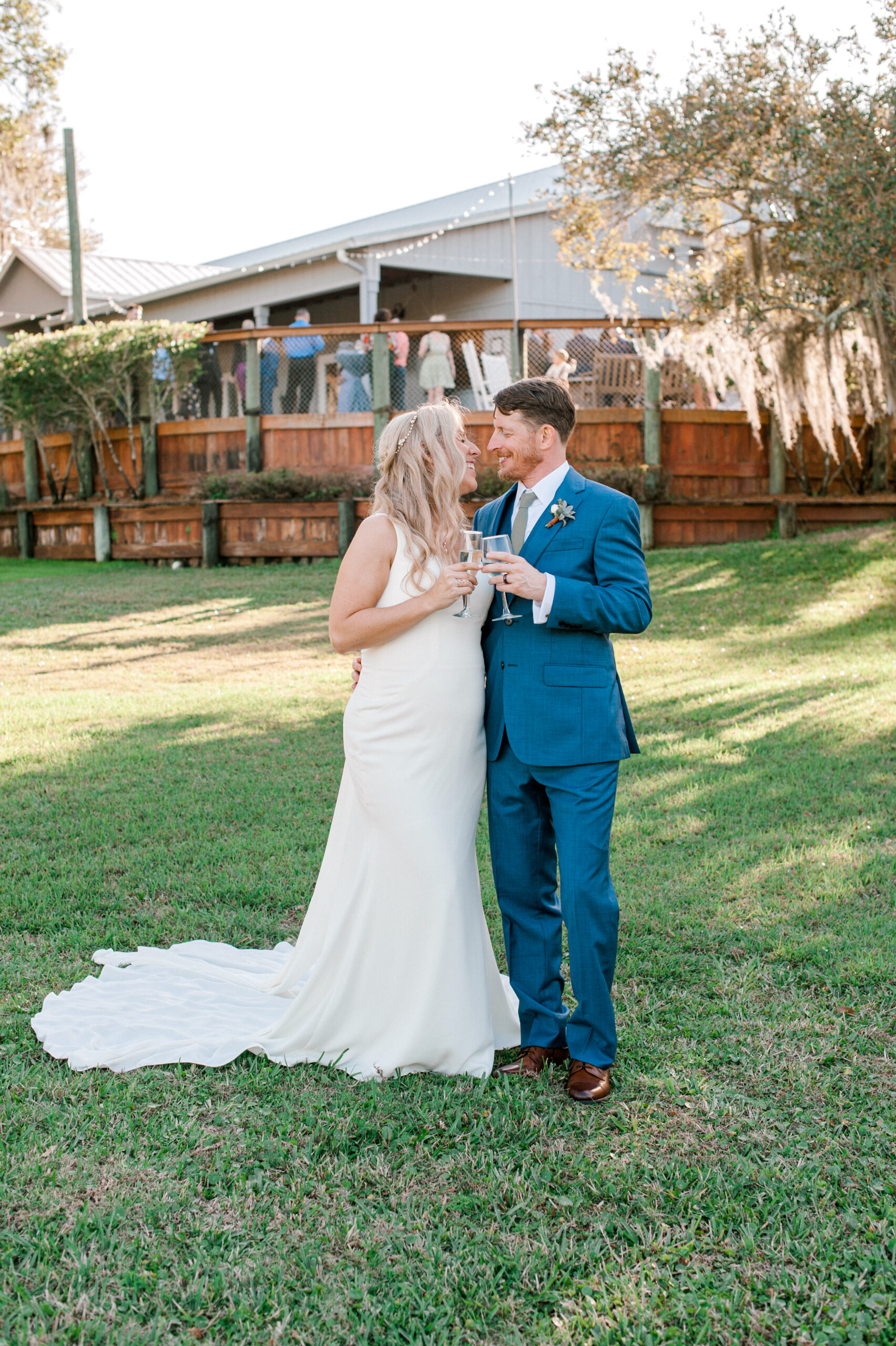 The boathouse at Up The Creek Farms is the perfect reception area and makes a beautiful backdrop for a photo of the bride and groom with guests behind them on their wedding day.