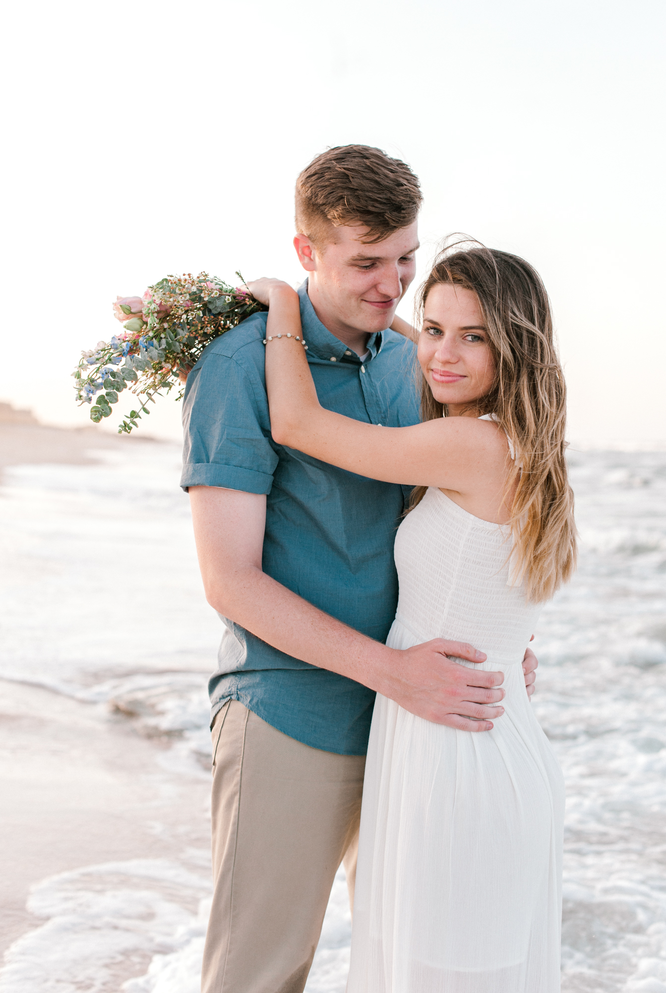 Newly engaged couple nuzzled close standing on the coquina rocks on the beach side of Washington Oaks Gardens State Park.