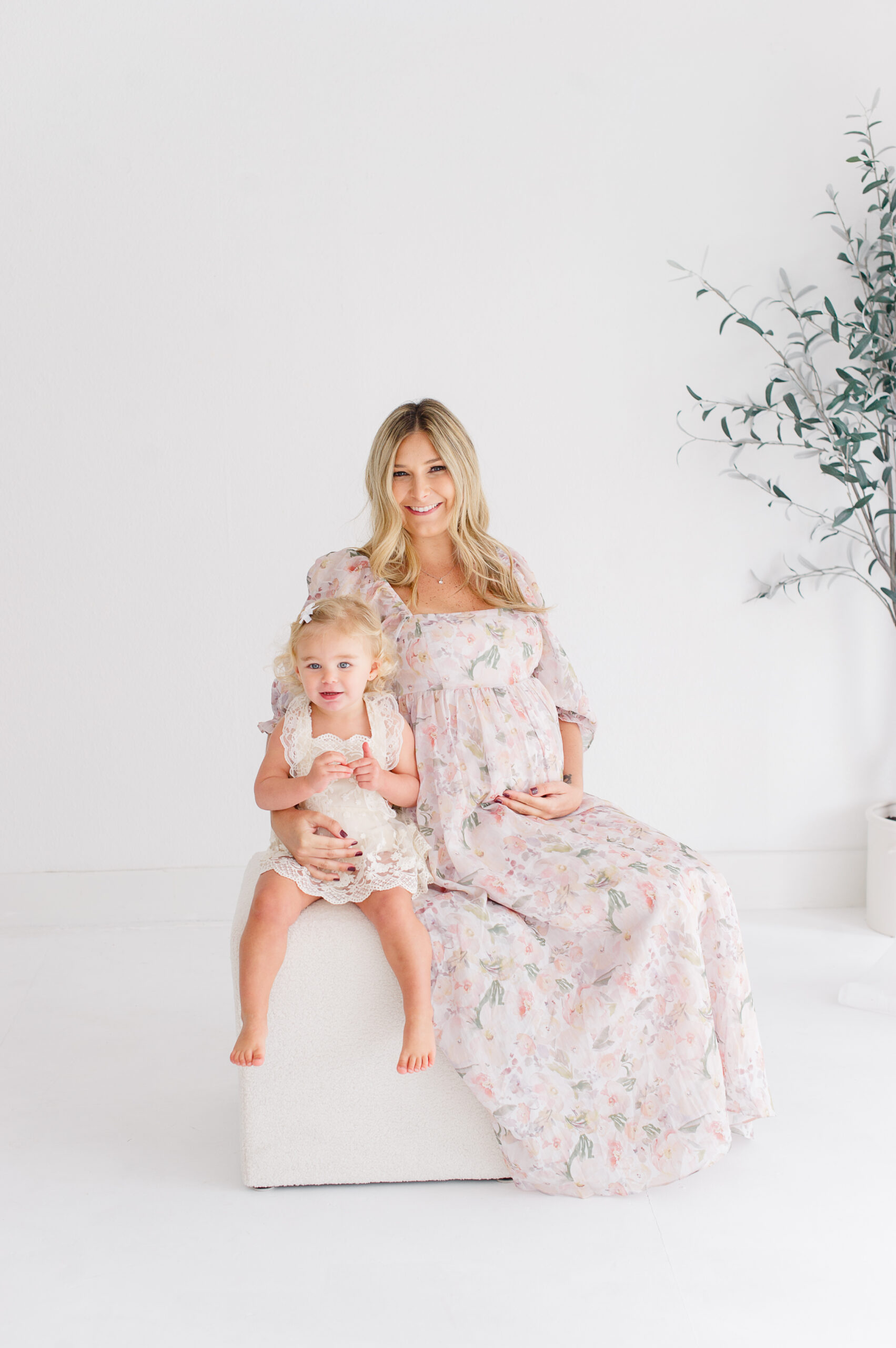 Pregnant mom sitting with her young daughter in a natural light photography studio baby boutiques Orlando