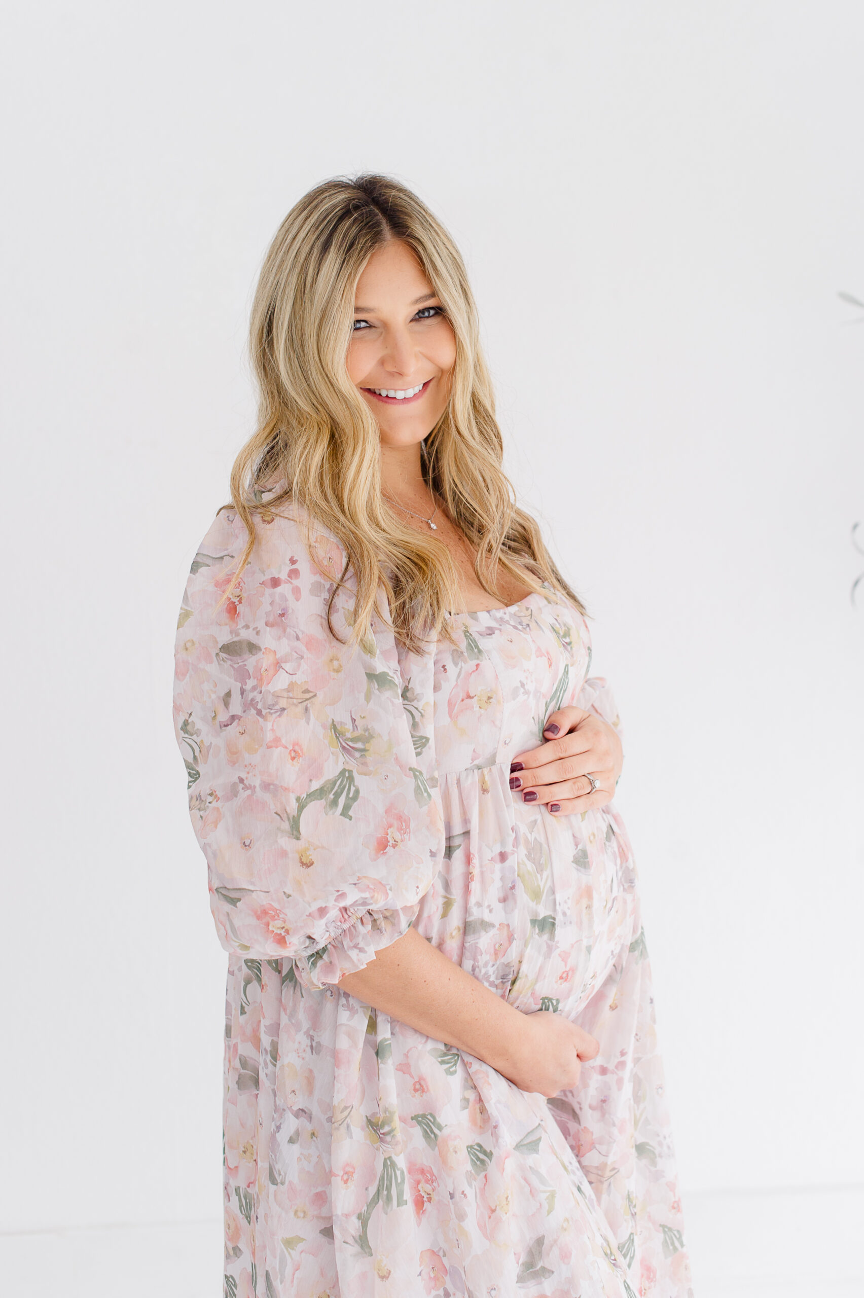 Expectant mother holding her belly and smiling at the camera baby boutiques Orlando
