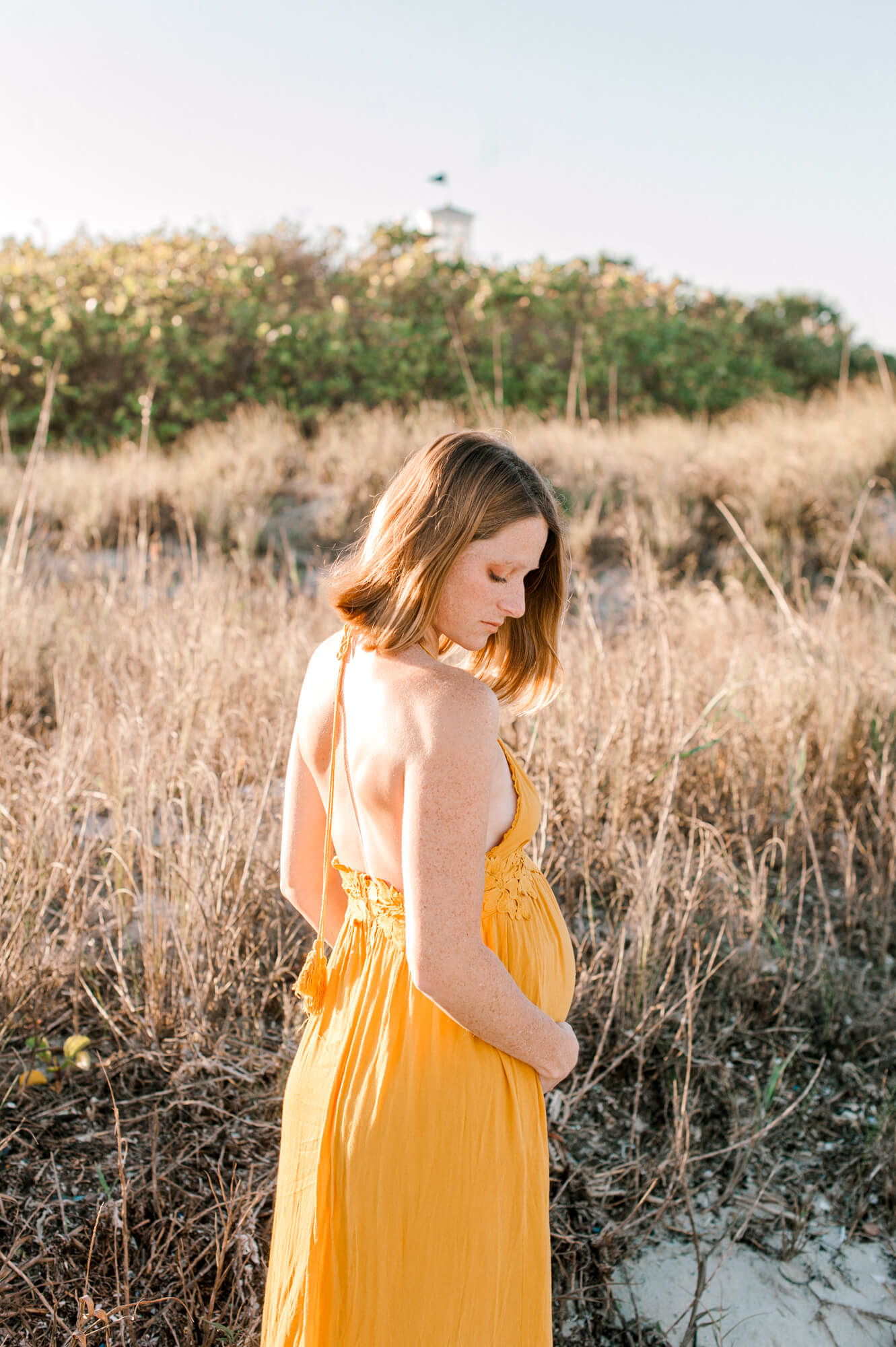 Expectant mom holding her belly and looking down thinking of her birth experience at beautiful beginnings midwifery in Melbourne, Florida.