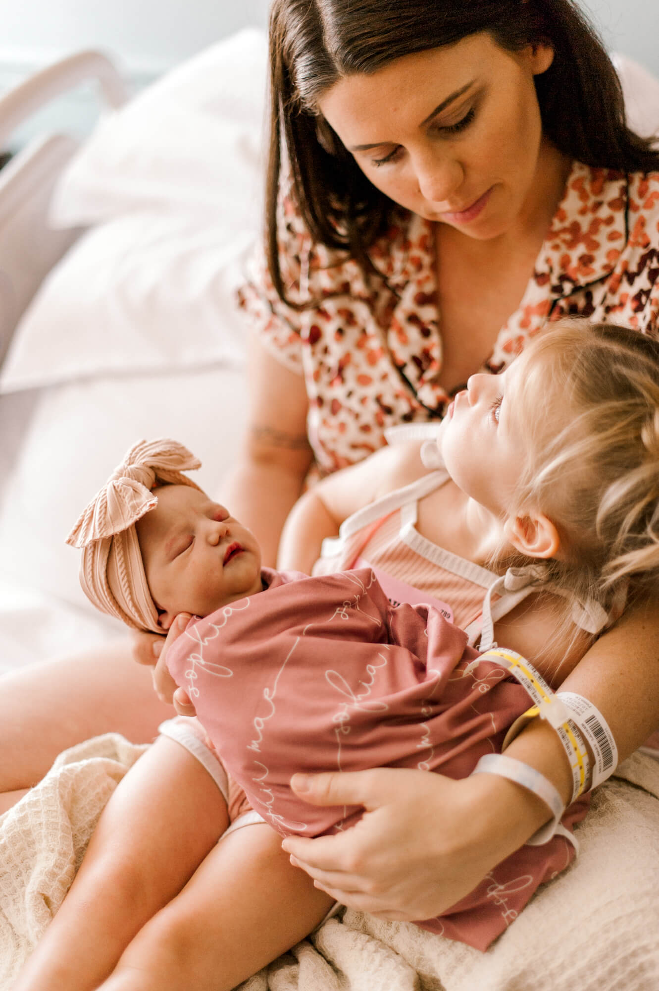 New mother holding her two daughters shortly after birth as they meet for the first time at Holmes Labor and Delivery.