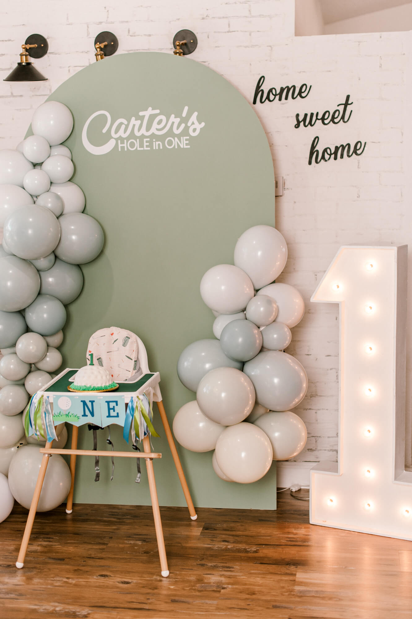 The cutest cake smash backdrop of a first birthday hole in ONE theme with highchair and cake. 