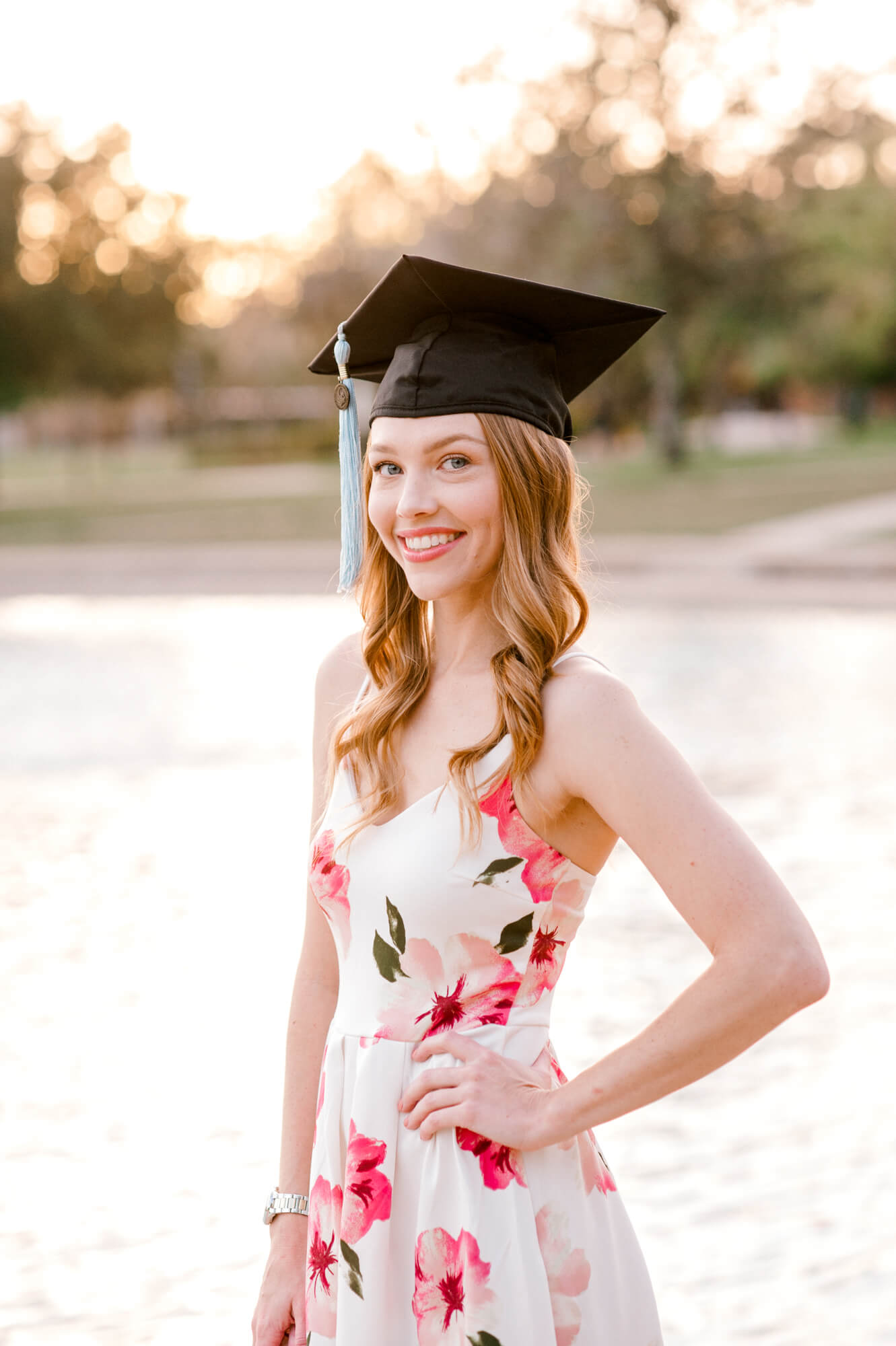Student standing in front of the reflection pond with her hand on her hip in her cap for her UCF graduation photos. 