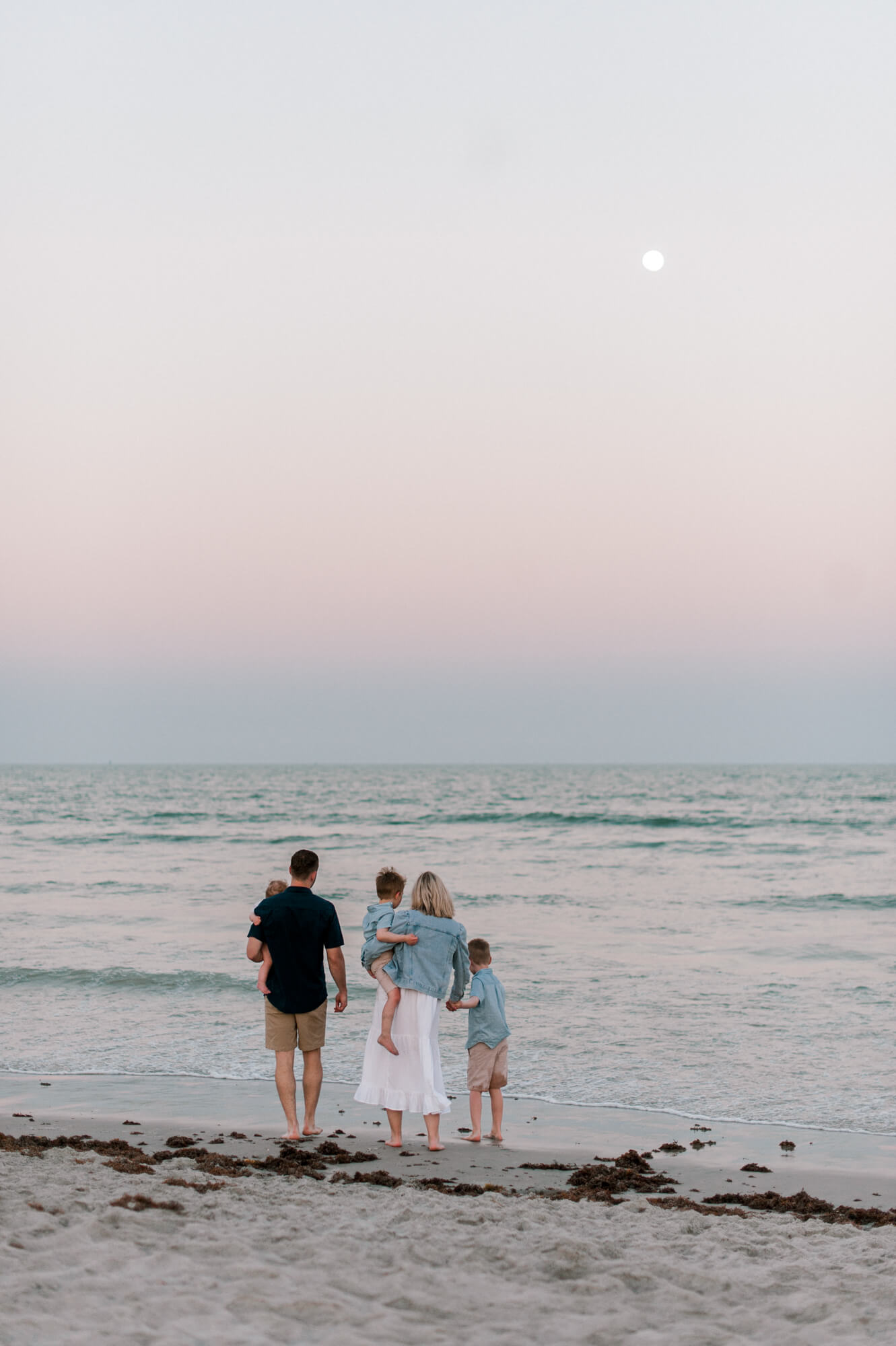 Family watching the waves and looking at the moon at sunset on Cocoa Beach. Viera Pediatric Dentistry would be a wonderful fit for their 3 children. 