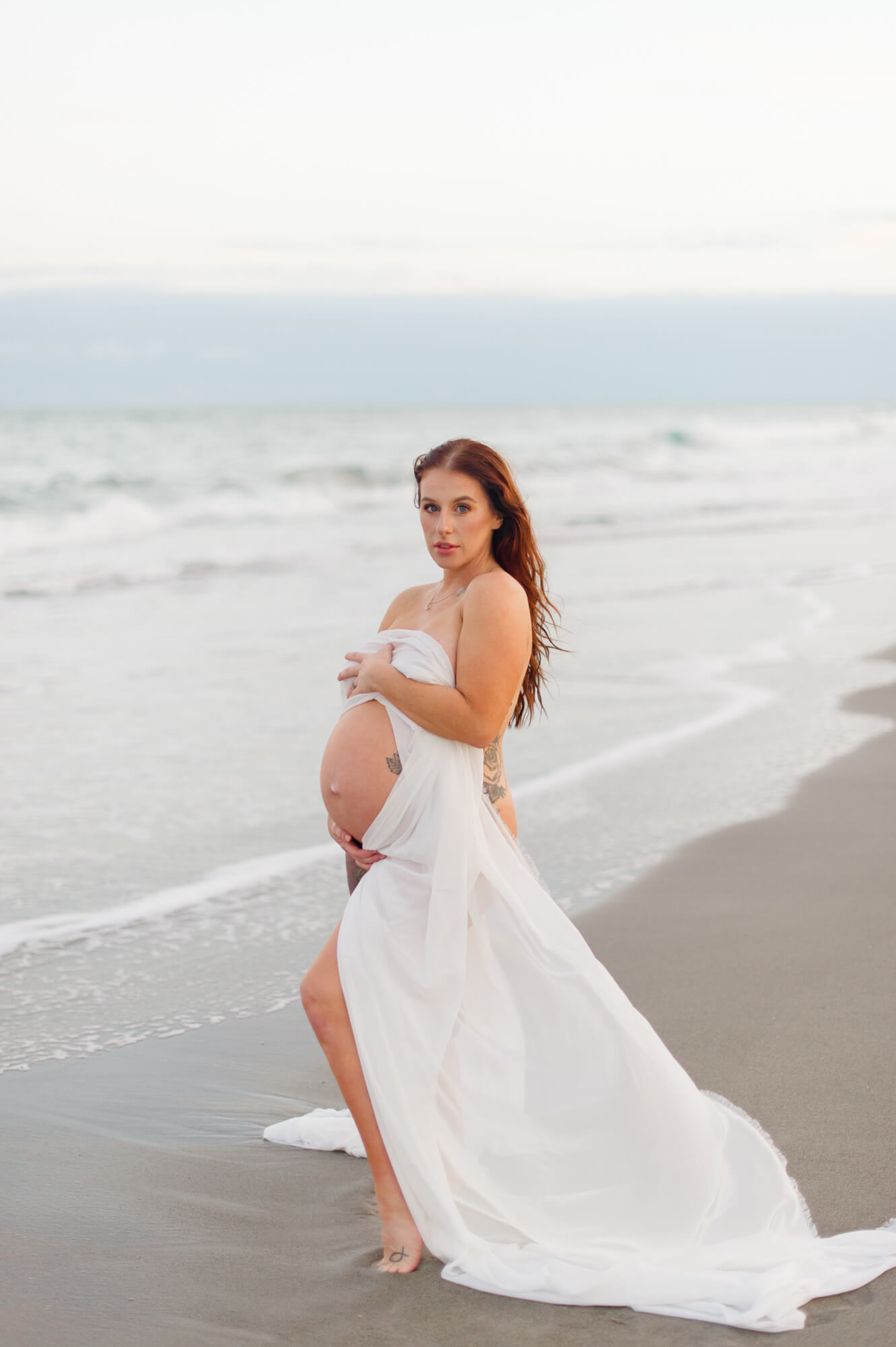 Pregnant mother standing on the beach holding chiffon showing off her baby bump 3D ultrasound Melbourne FL