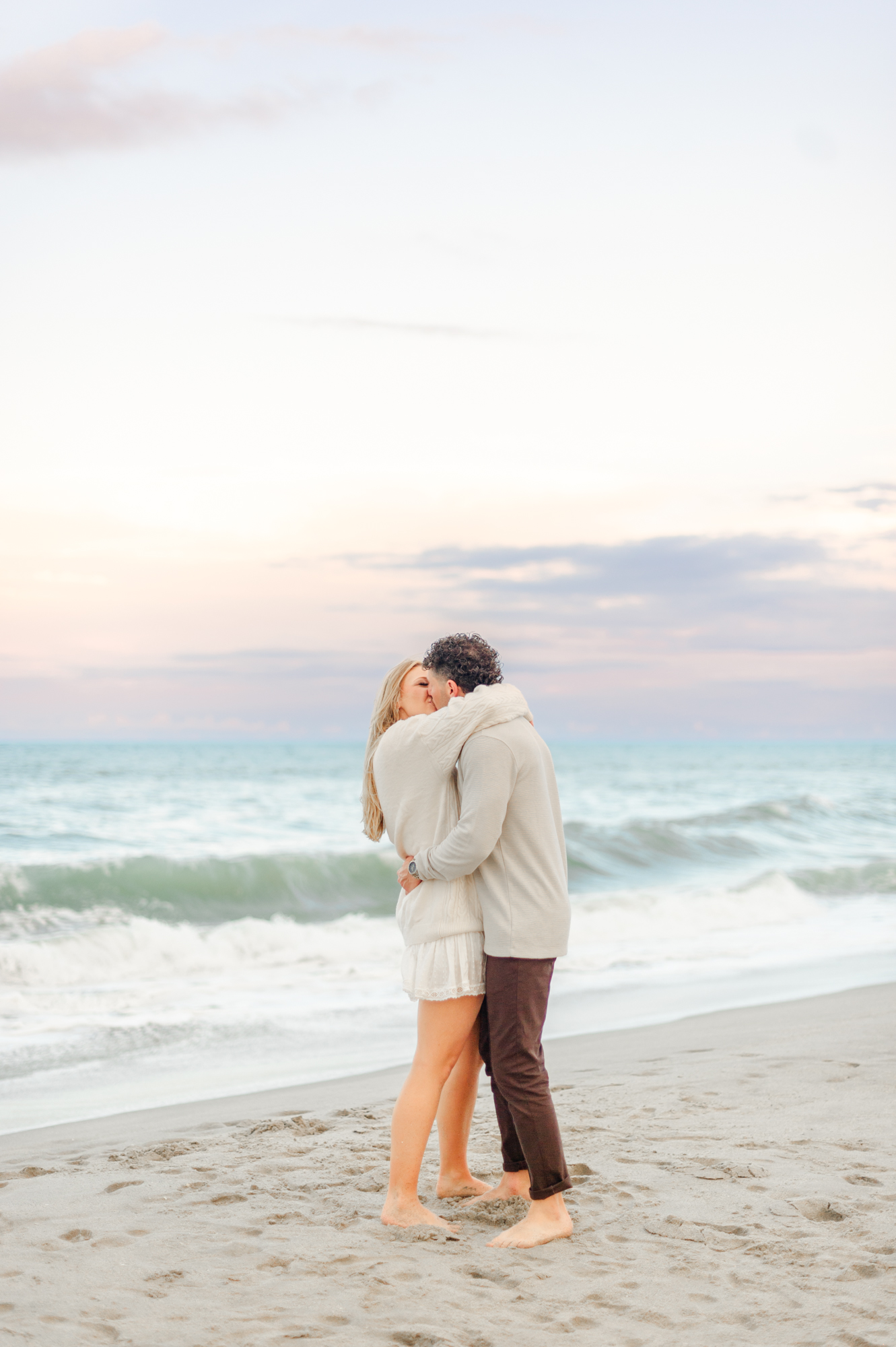 Couple kissing near the shoreline on the beach in Melbourne Beach, FL during their luxury picnic with A Picnic Affair.