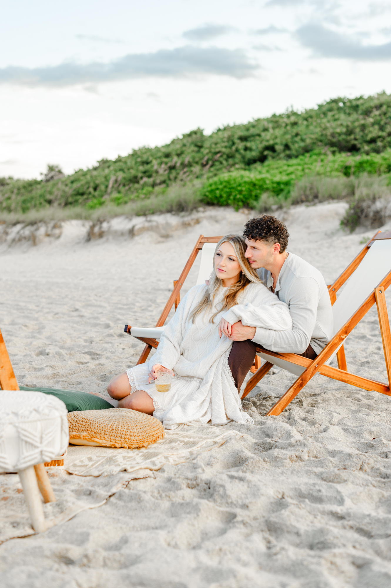 Stunning couple enjoys a beautiful luxury picnic on the beach for a fall date night.