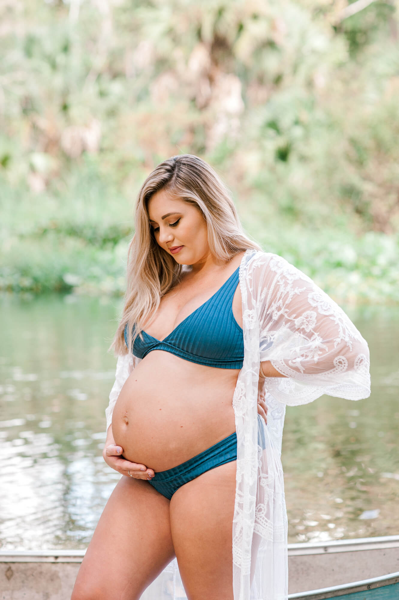 New mom stands near the springs in Orlando in her bathing suit holding her belly and dreaming of what her little one will look like and what her experience with Sacred Birth Midwifery will be like. 