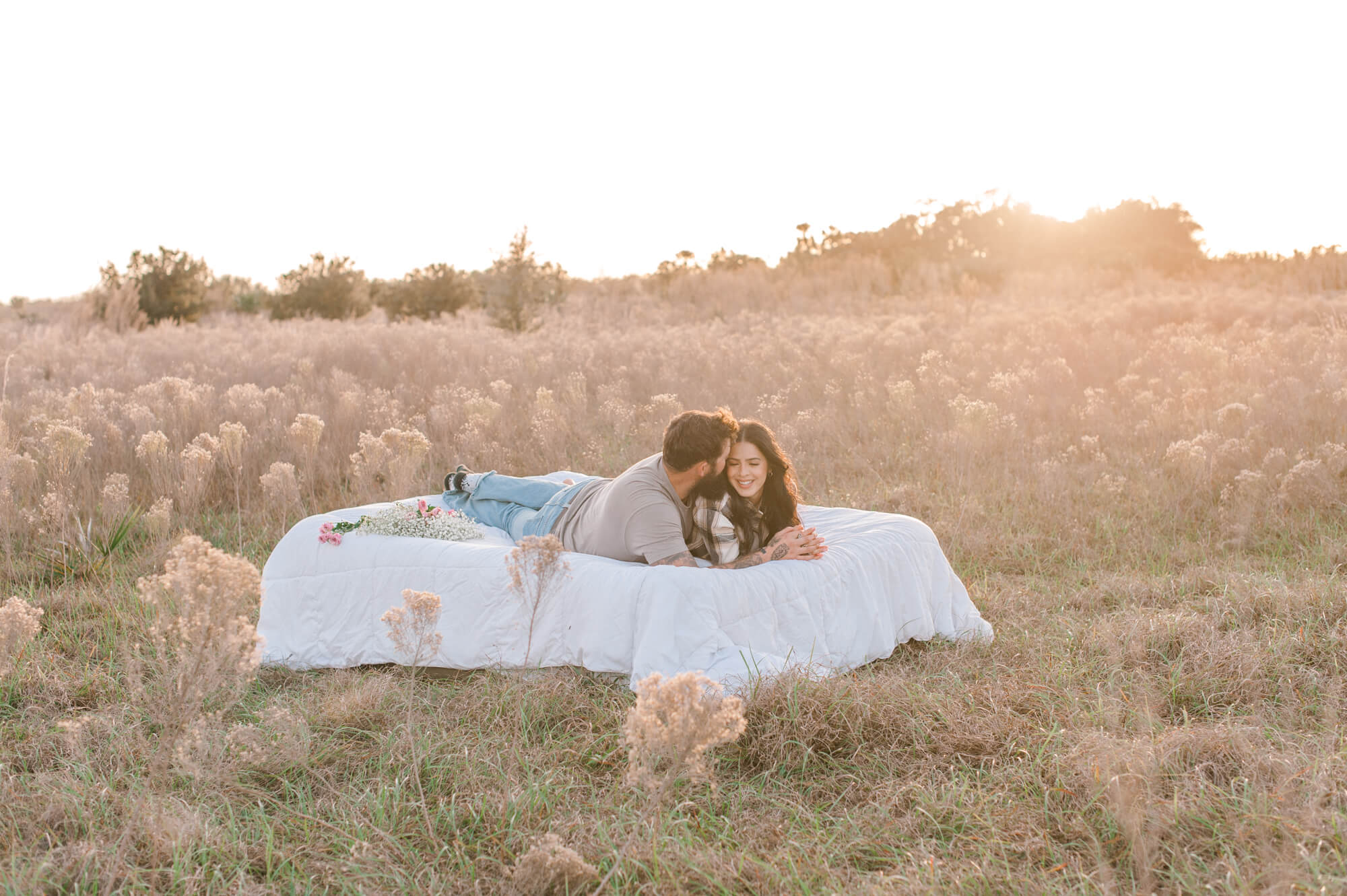 Stunning sunset photo with a golden hour glow of a couple laying together on an air mattress in the middle of a field talking about the yoga garden in Orlando, Florida.
