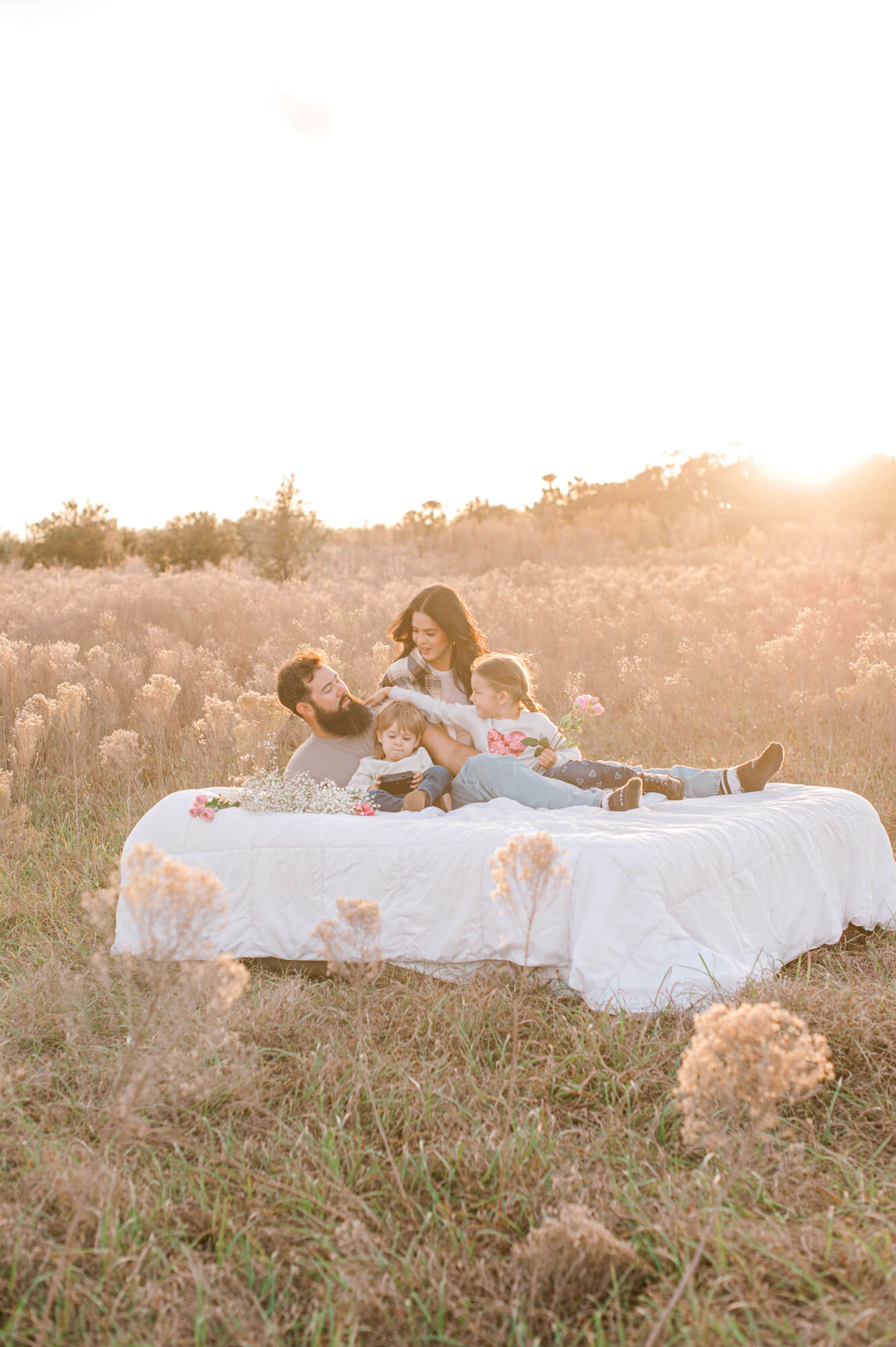 The sweetest family cuddled up at sunset on an air mattress in the middle of a cow field.