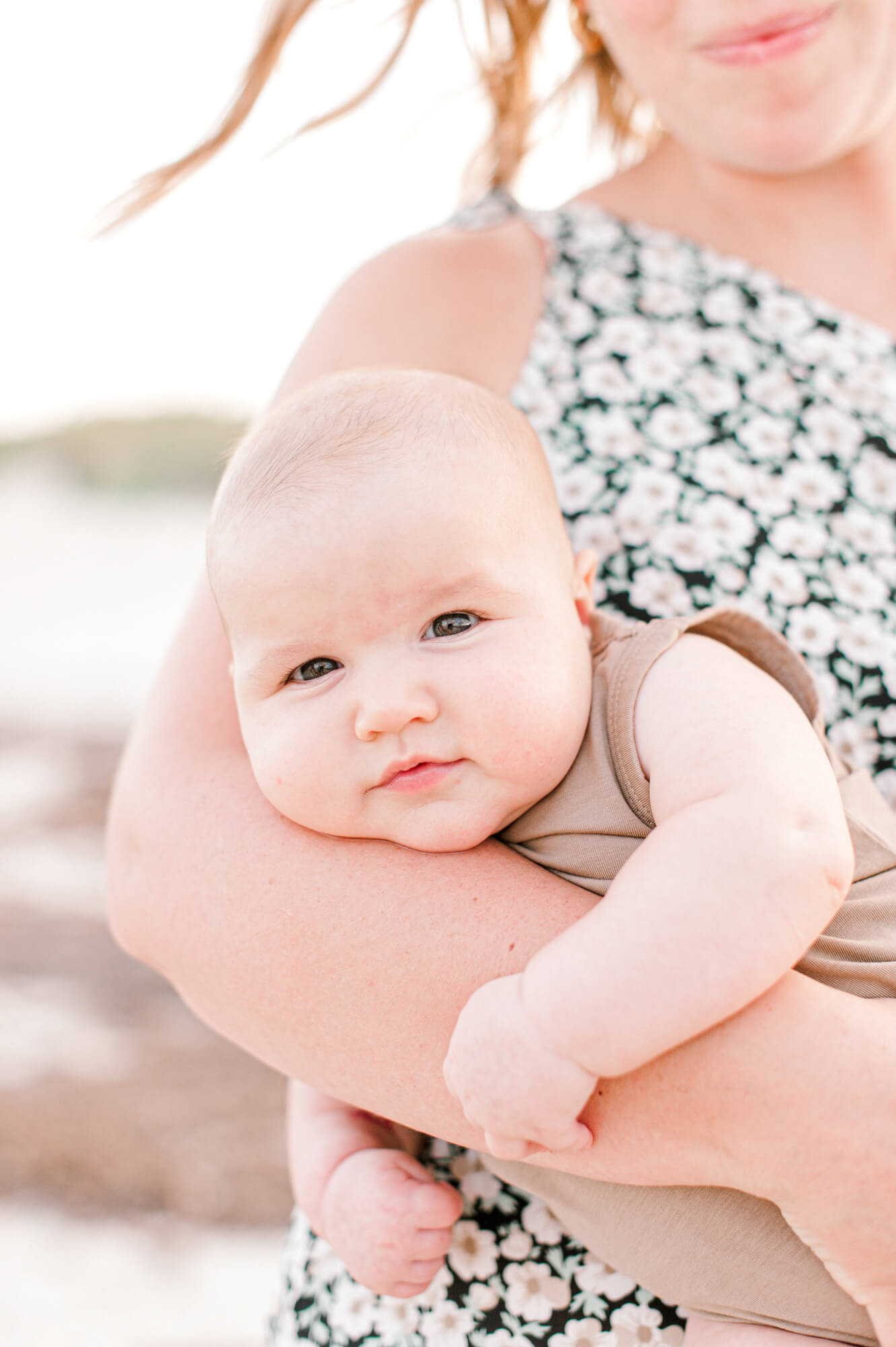 Sweet chunky 3 month old baby boy in moms arms at sunset in Jetty Park near Orlando, Florida.