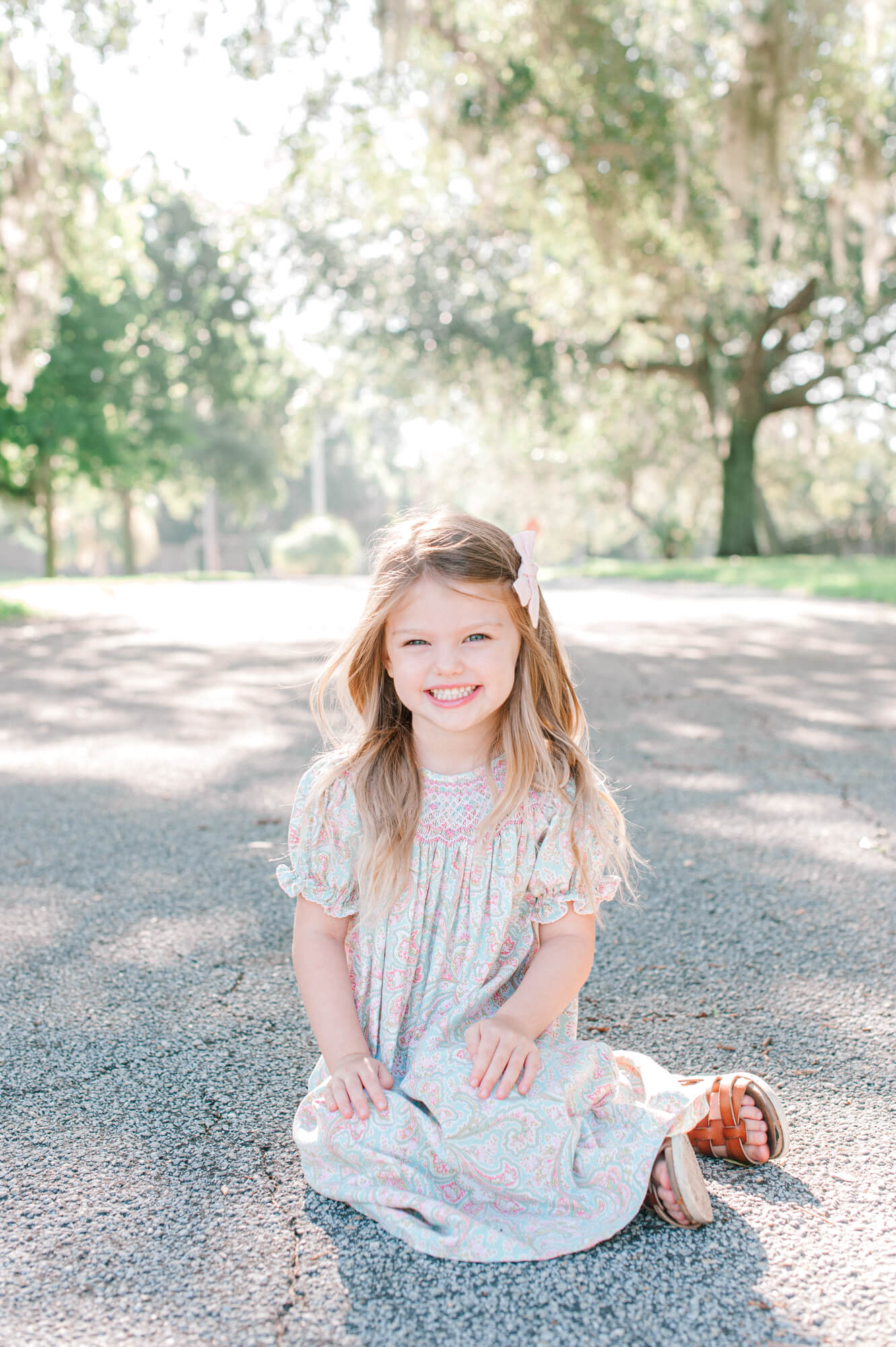 Portrait of a young girl in a floral dress smiling at the camera near a park baby wheels orlando