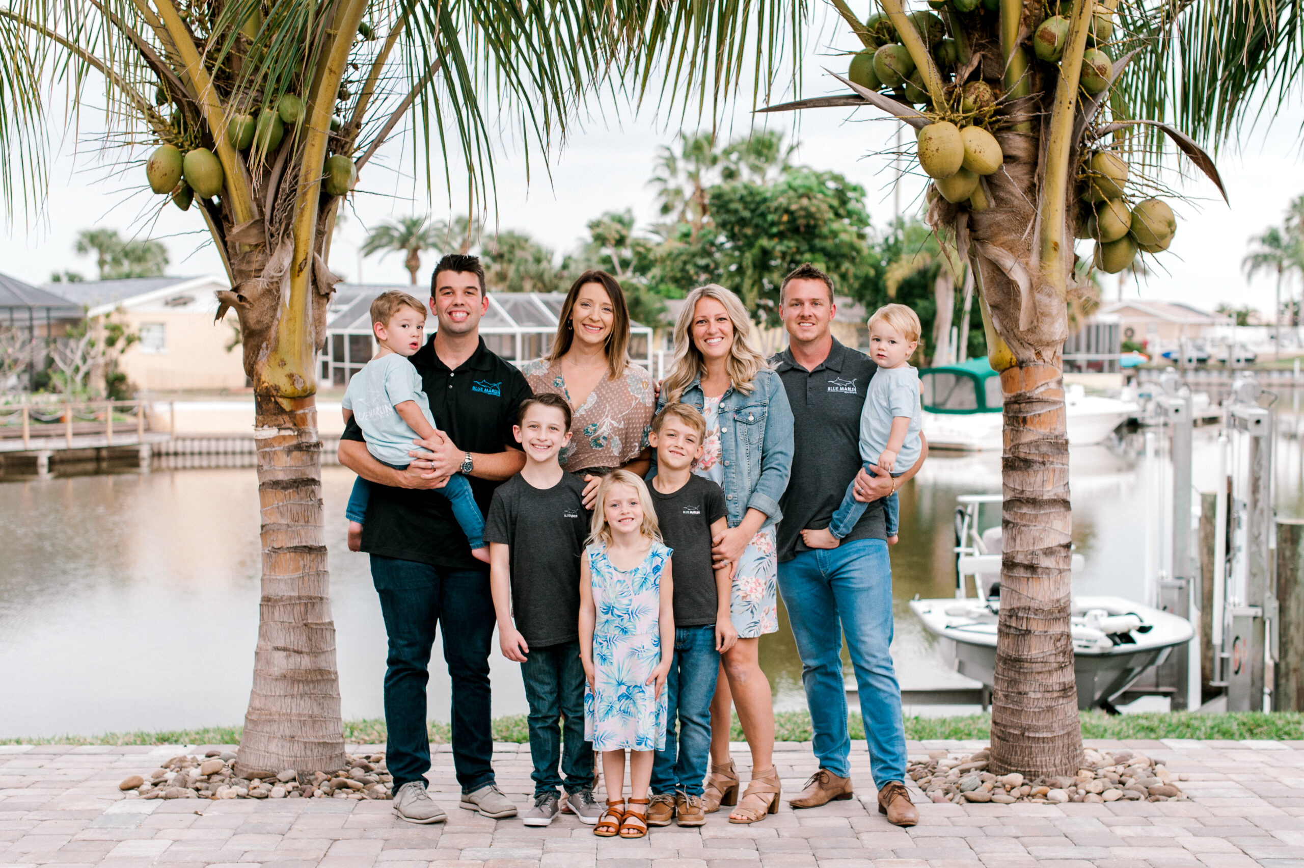 Blue Marlin Real Estate owners stand with their families for a portrait on a dock in front of the canal in Merritt Island, Florida