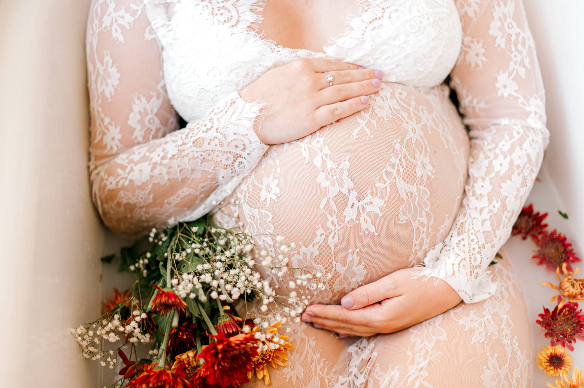close up belly photo of soon to be girl mom holding her belly in a lace dress with florals orlando midwives
