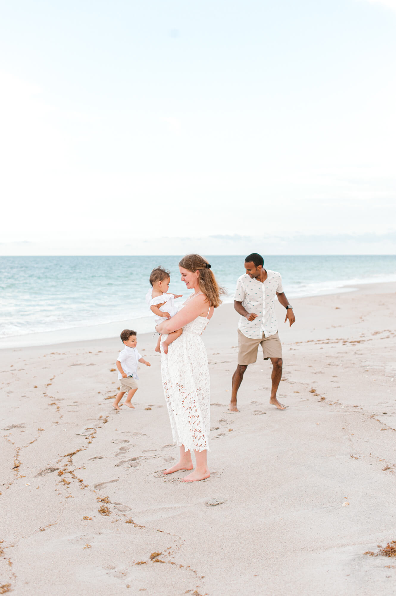 Family of four playing on the beach during their session at sunset, stroller rentals in Orlando would be perfect for them.