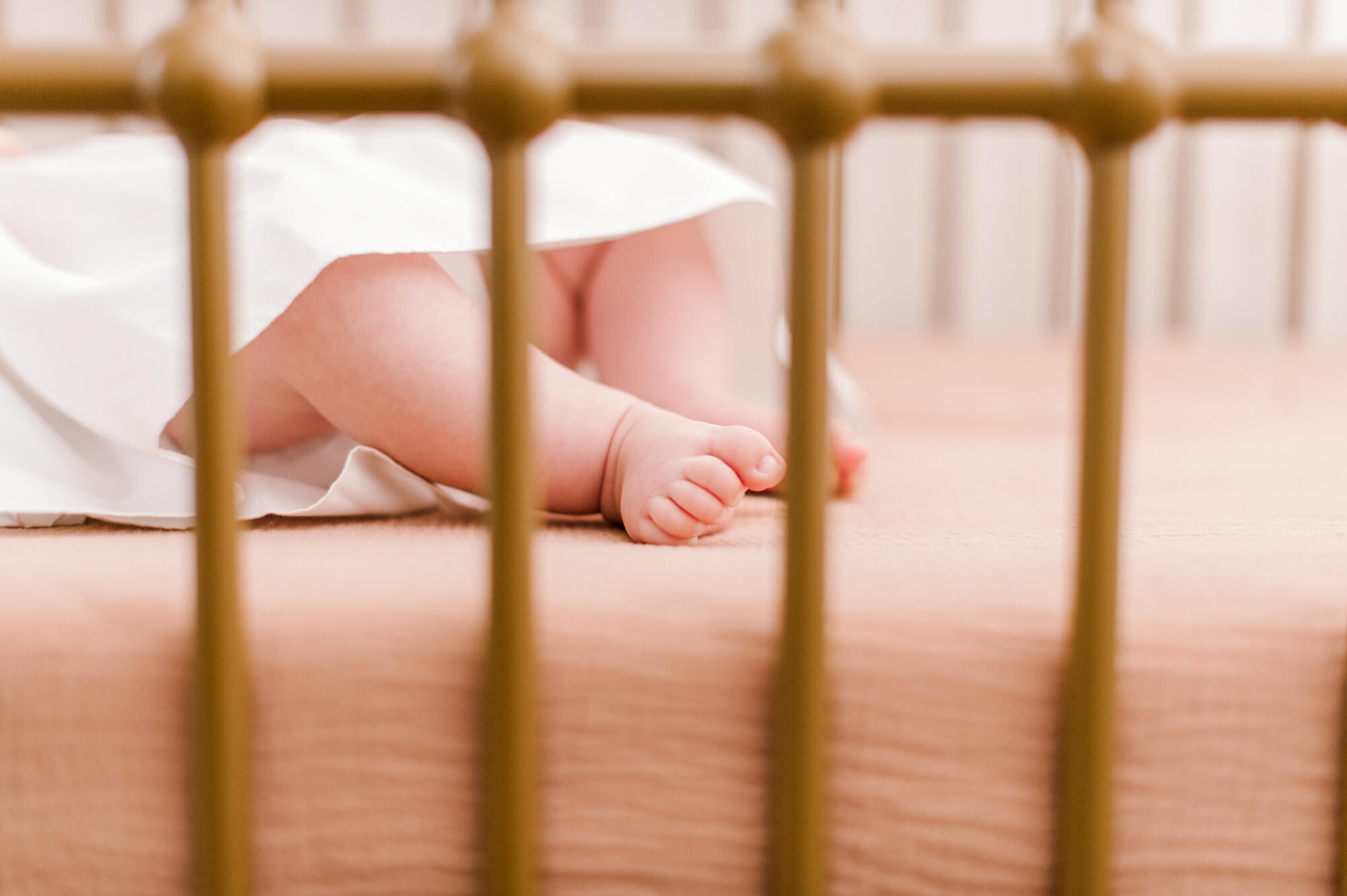 Ten tiny little toes seen through the bars of a beautiful golden crib, Surfside pediatrics would be a wonderful fit for this little human. 