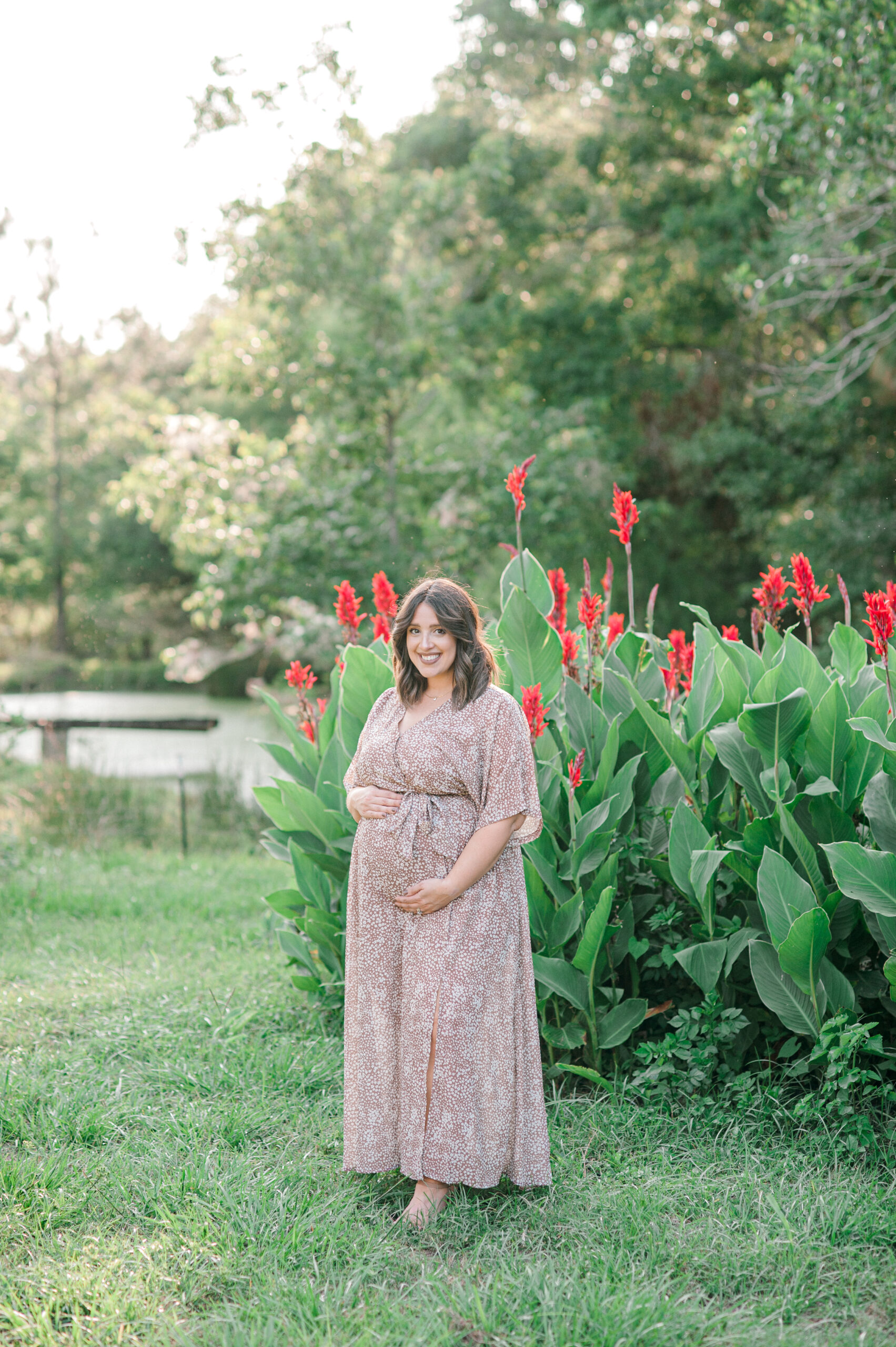 Full body photo of mom smiling at the camera while holding her belly during her maternity session the perinatal center
