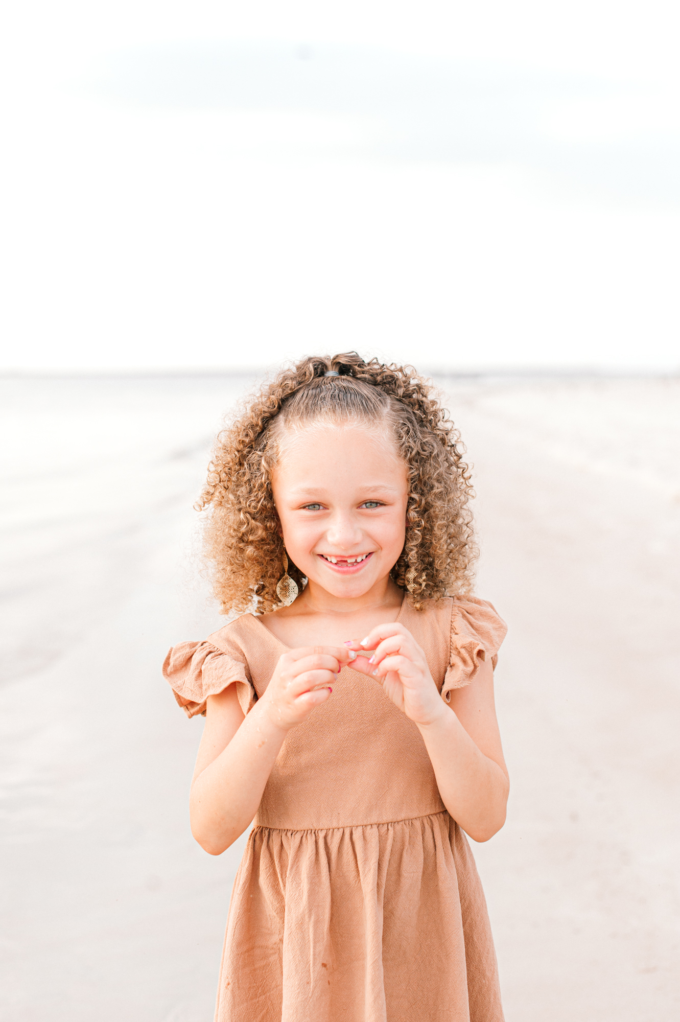 Young girl smiling at the camera near the water at the ocean during golden hour Orlando pediatricians 