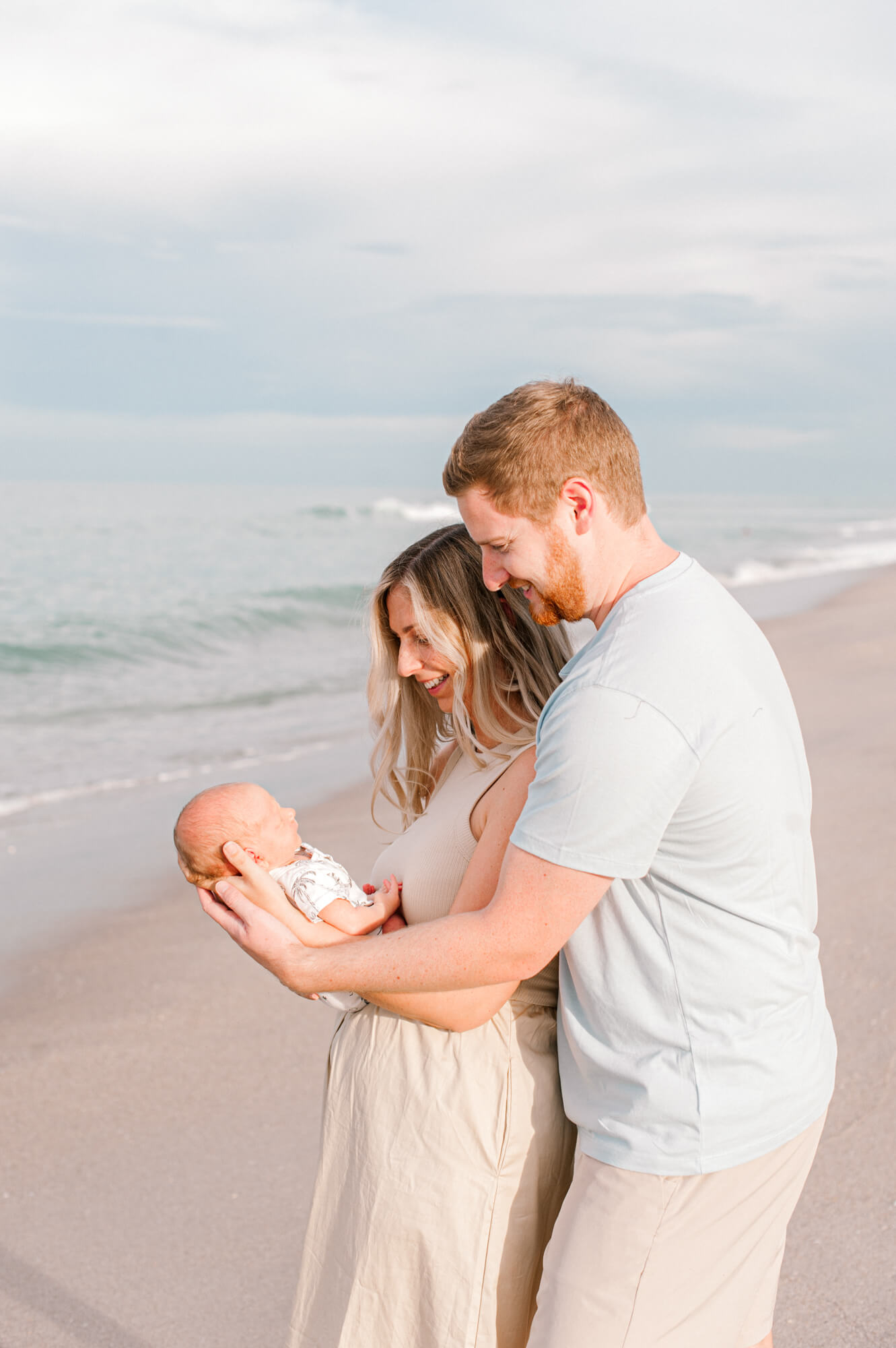 New parents stand near the waters edge while holding their sun and admiring him just a few weeks old.