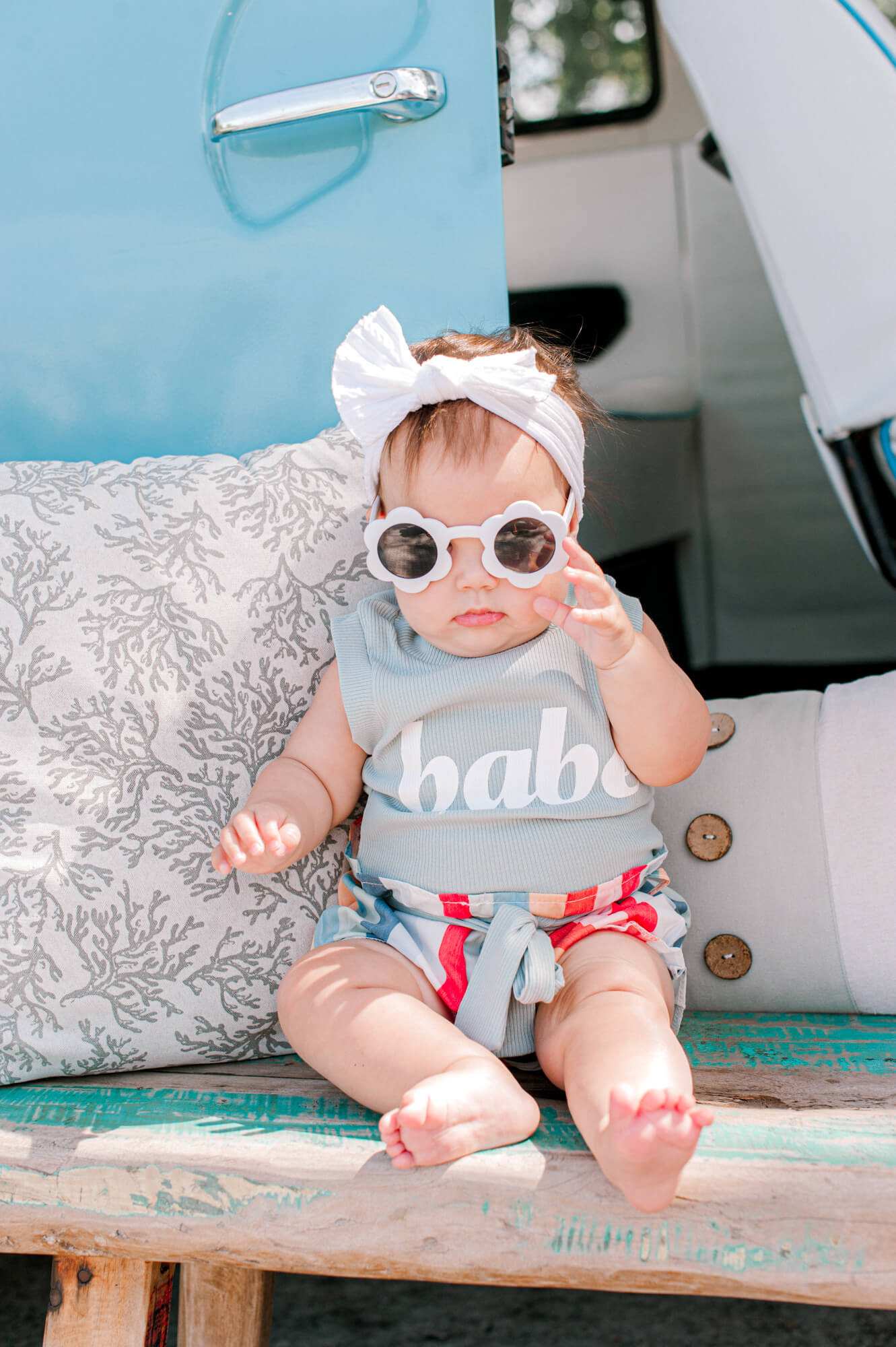 Adorable little beach baby holding her sunnies and looking at the camera on a hot summer day pediatric dentists in Orlando