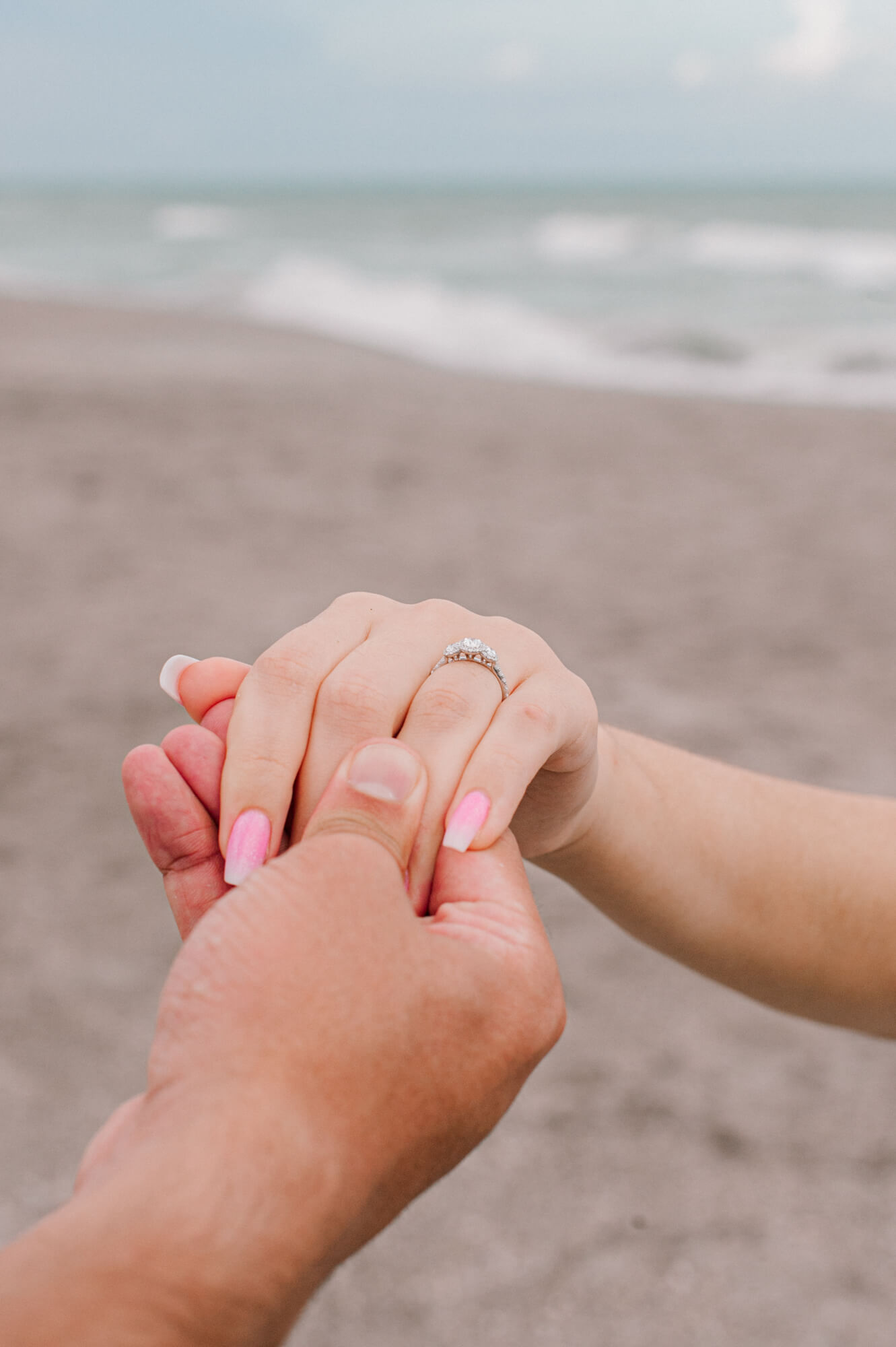 Beautiful close up of a man holding a womans hand with her engagement ring in focus on the beach spas in Daytona Beach