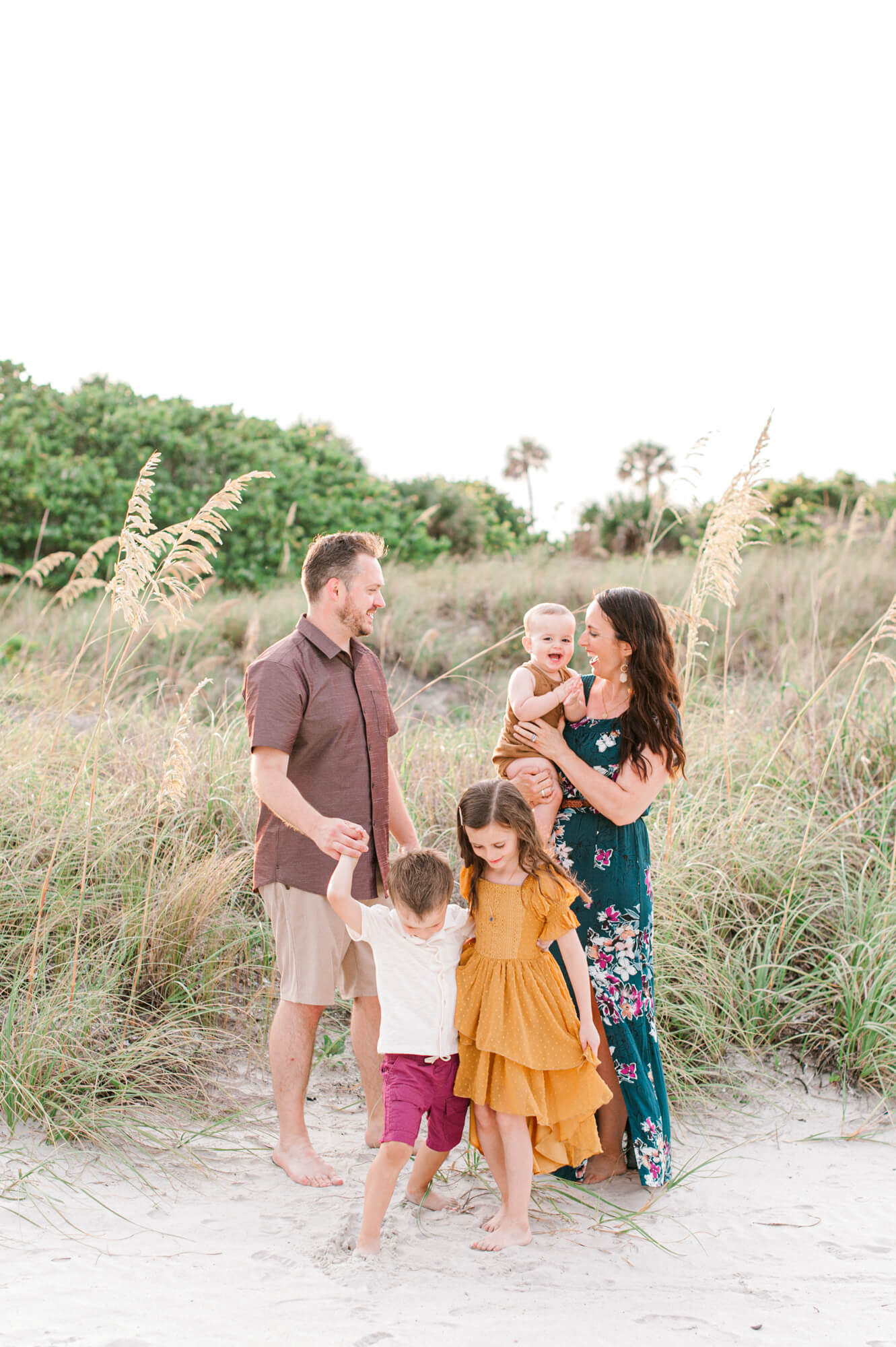 Family of five laughing at each other and playing in the sand during their Orlando Family Photographer session