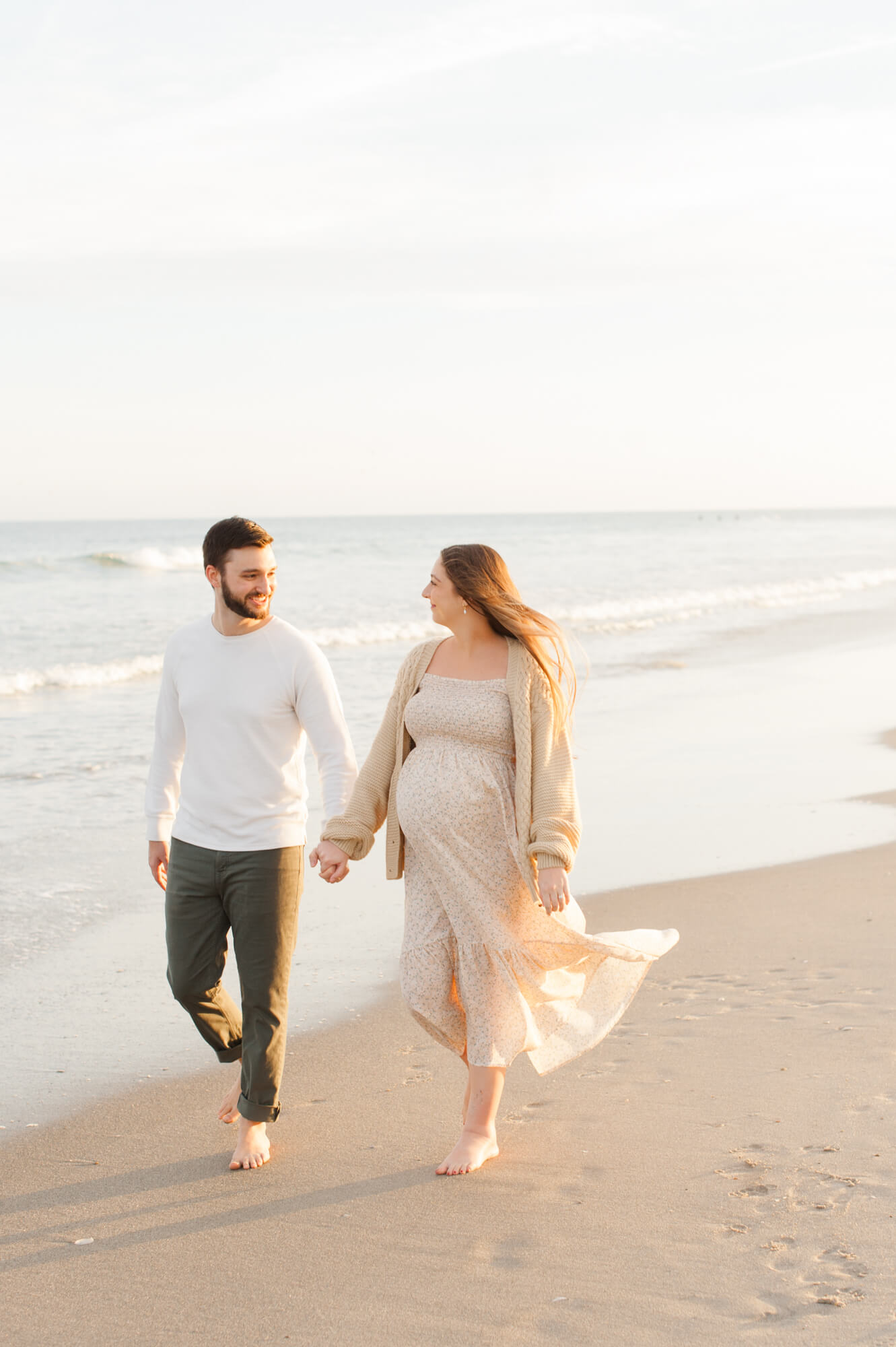Soon to be parents walk along the shore line on the east coast beach while dreaming of their baby girl buy buy baby orlando