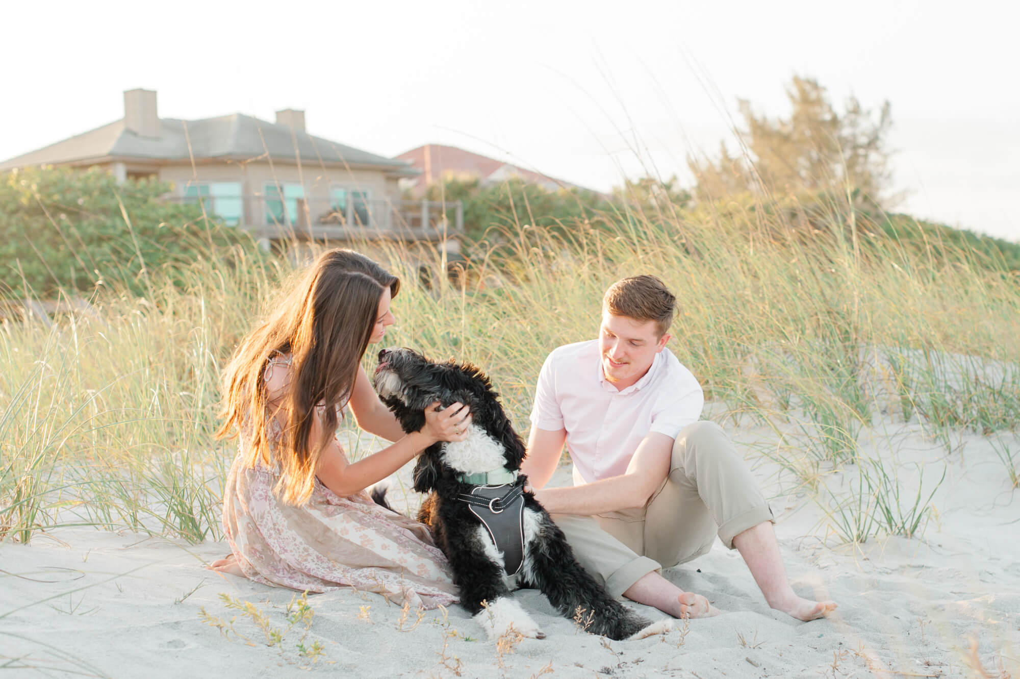 Couple giving their massive black golden doodle so much love while sitting in the dunes during their photoshoot Orlando yoga studios