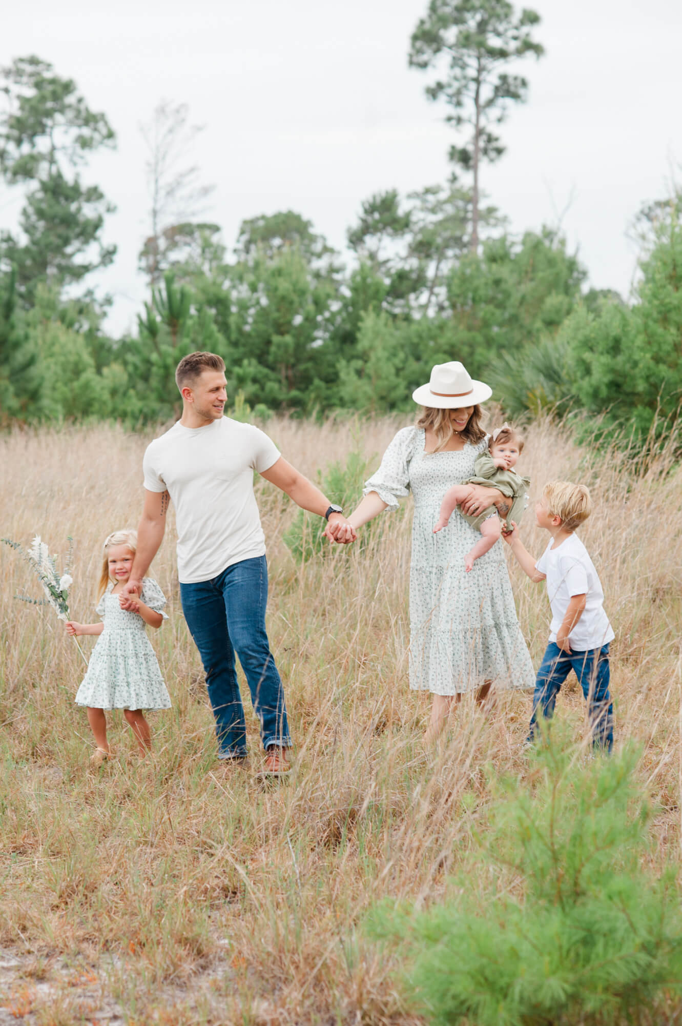 Family of five walking hand in hand in a tall grass field on a gloomy day Coastline family chiropractic