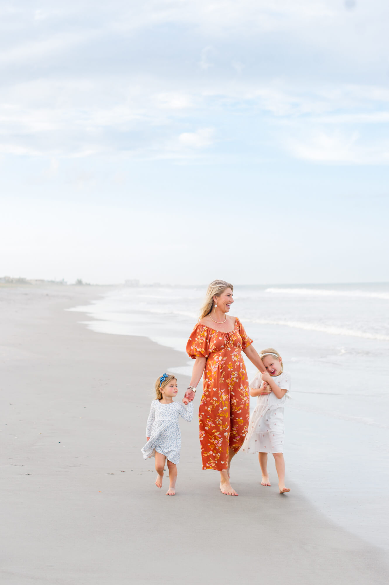 Beautiful image of grandma walking on the beach with her young granddaughters at sunset