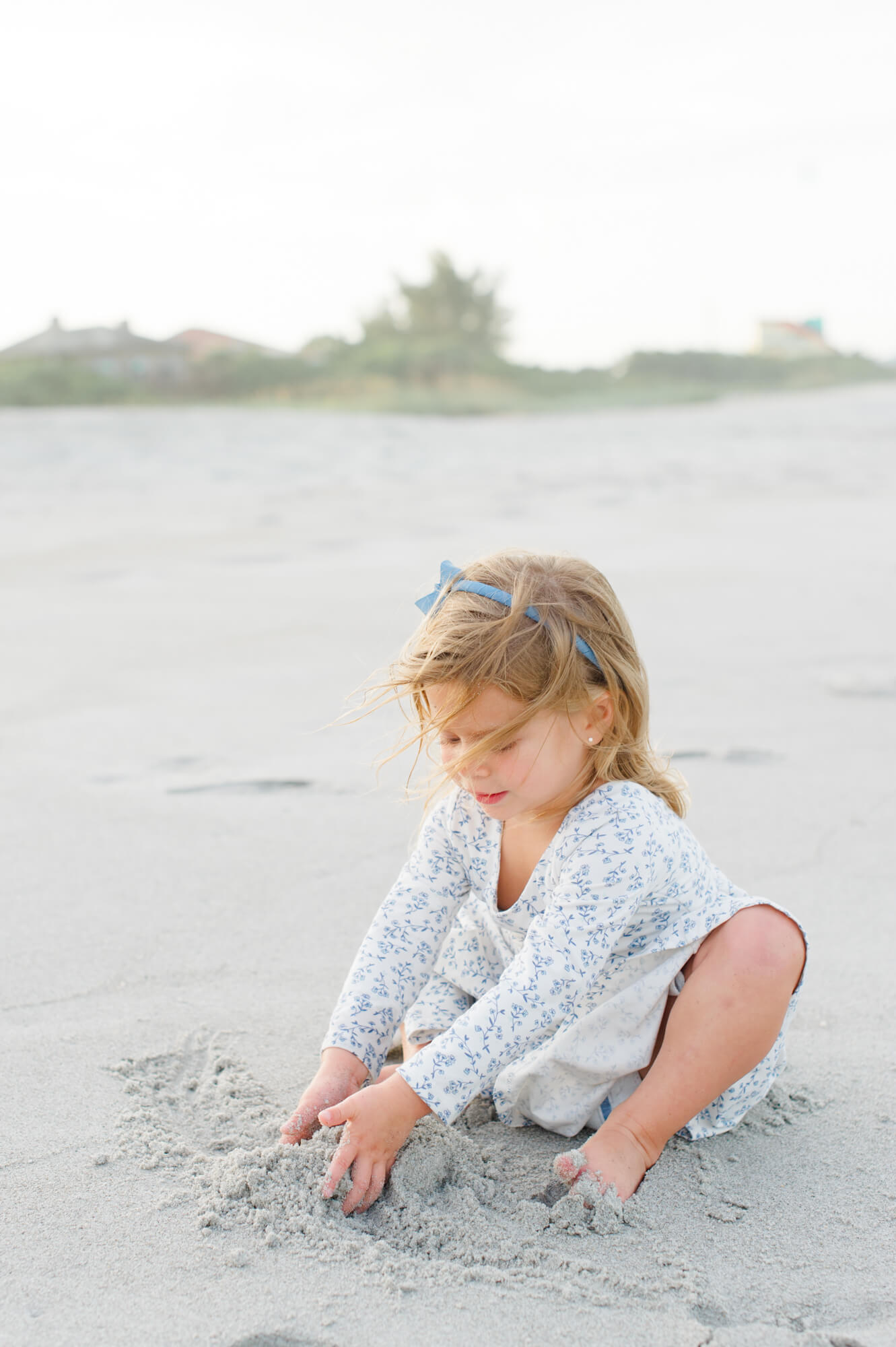 Young child plays in the sand at the beach during their Orlando family session Orlando toy stores