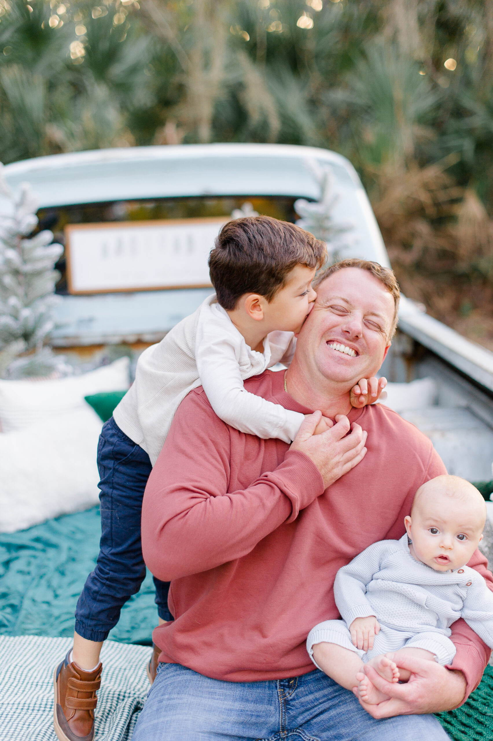 Dad being playful with sons on the back of a truck while oldest son kisses his head Orlando babysitters
