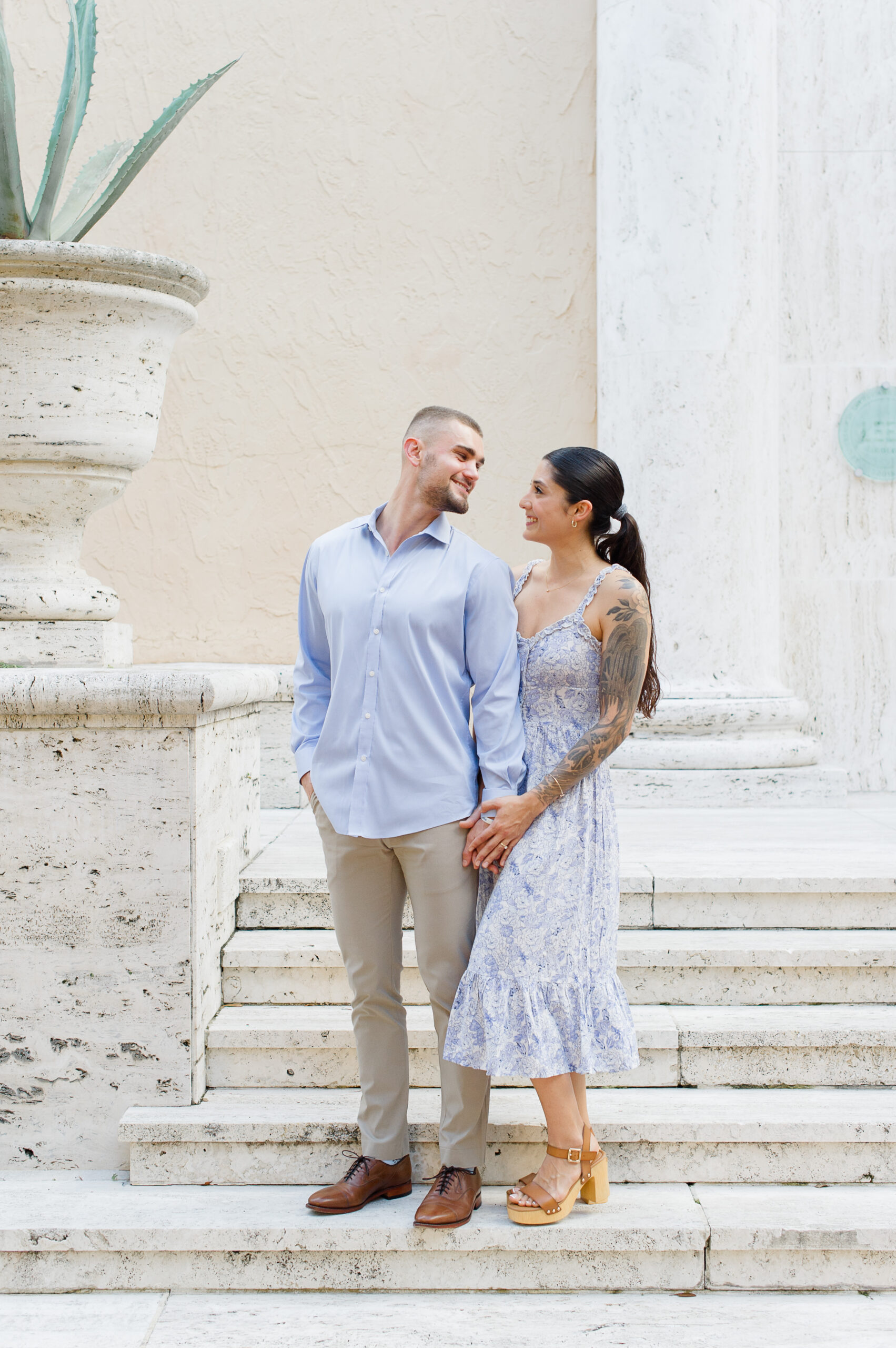 Stunning couple standing on the steps at Rollins College looking at each other.