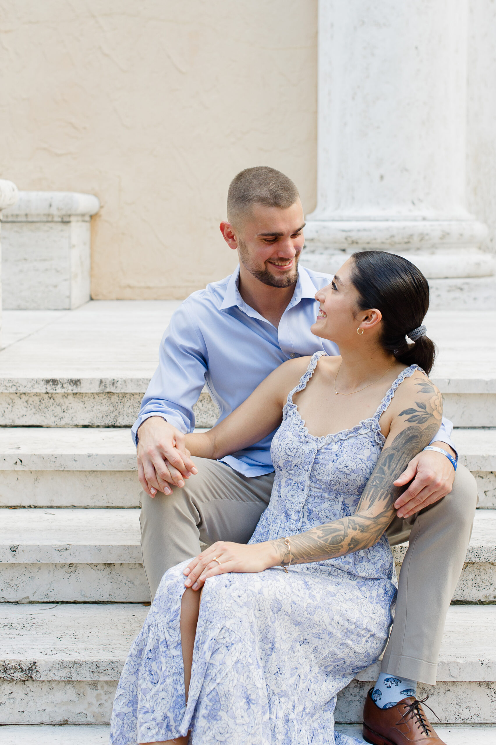 Adorable couple wearing beautiful blue tones sitting on the steps at Rollins College