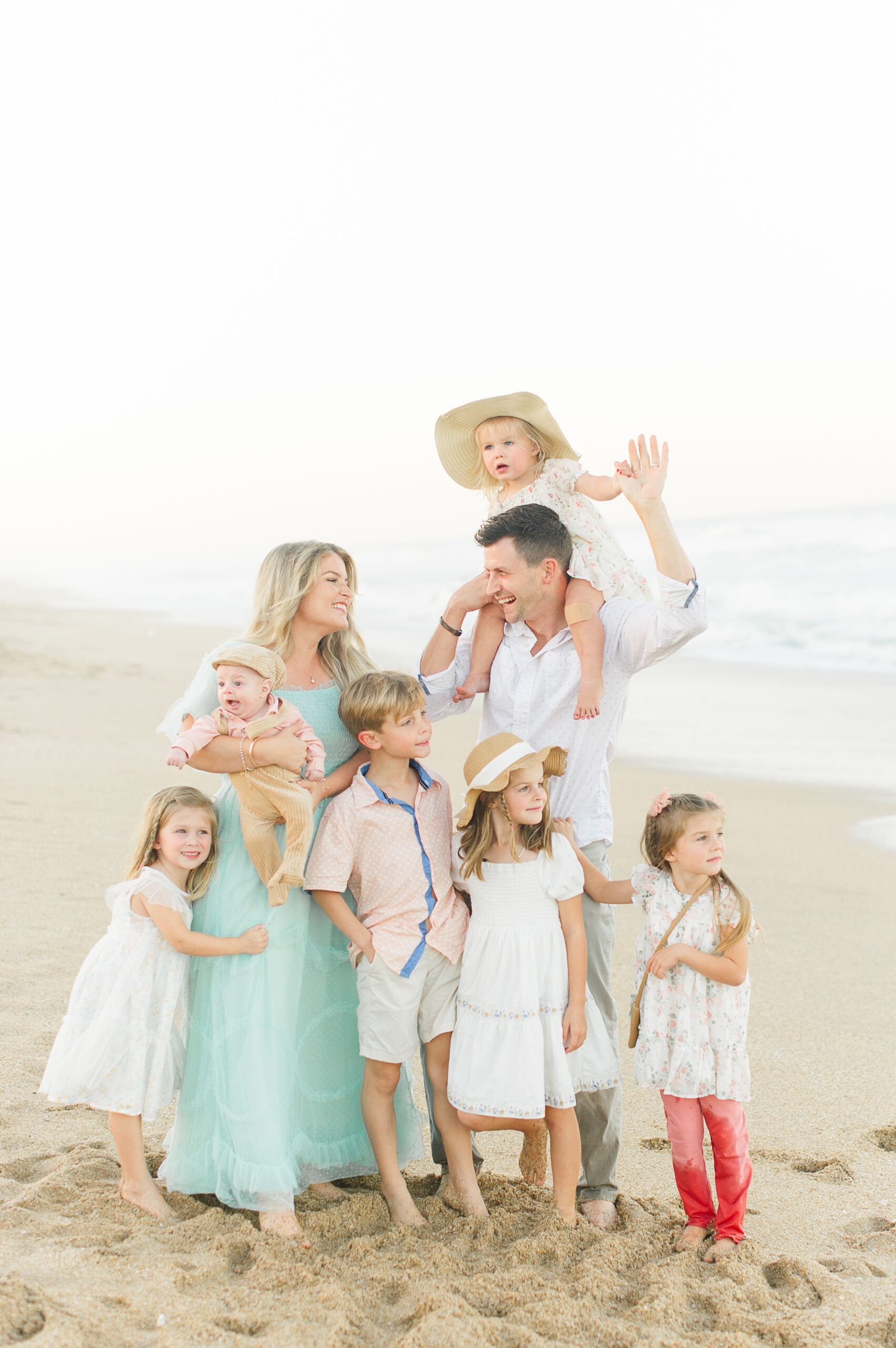 Sweet family of 8 laugh and play on the beach while M. Lauren Photography captures their family during their family beach session with a Daytona Beach family photographer