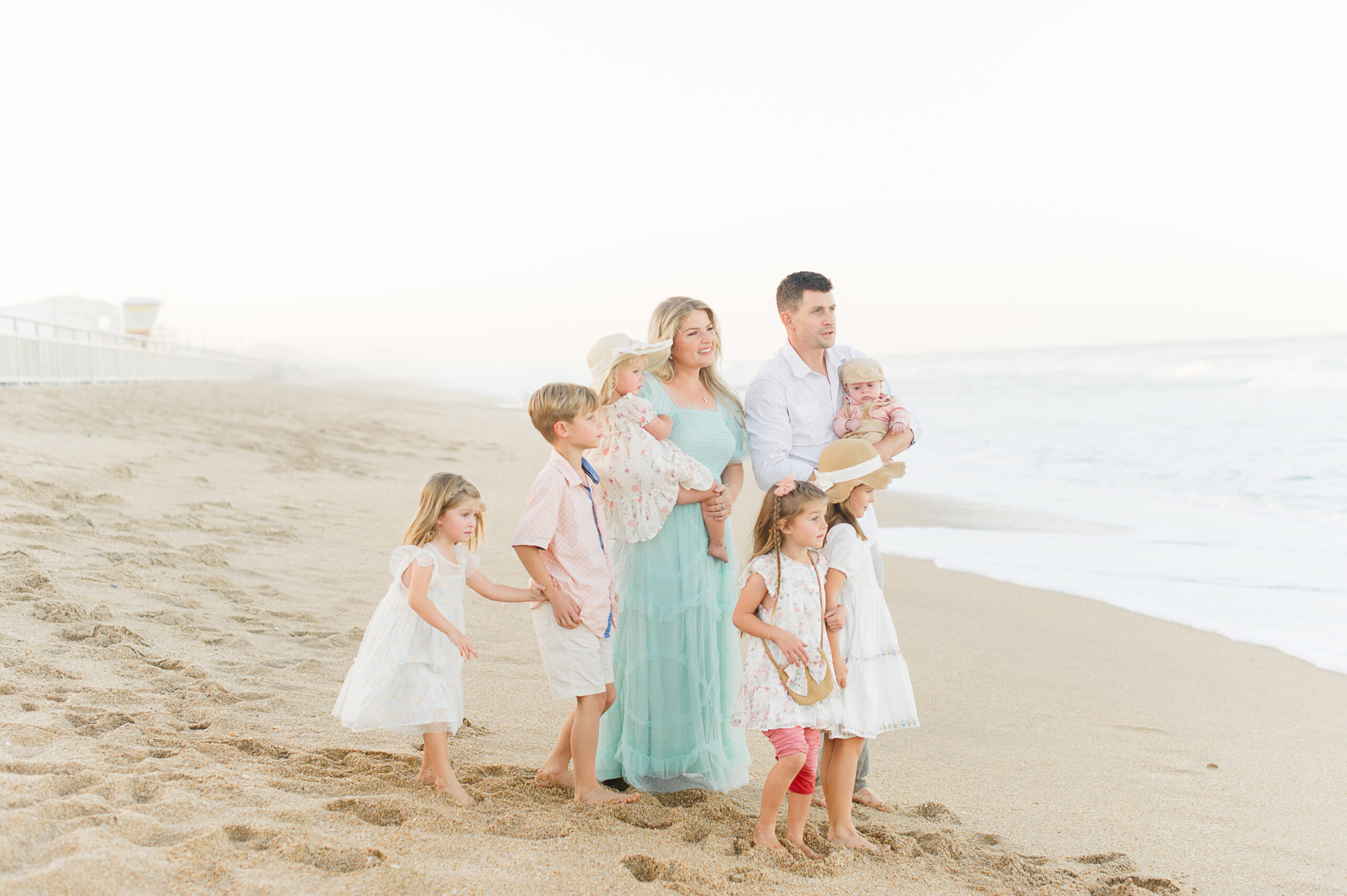 Stunning image of a beautiful family of eight watching the waves crash on the beach during their family beach session with a Daytona Beach Photographer