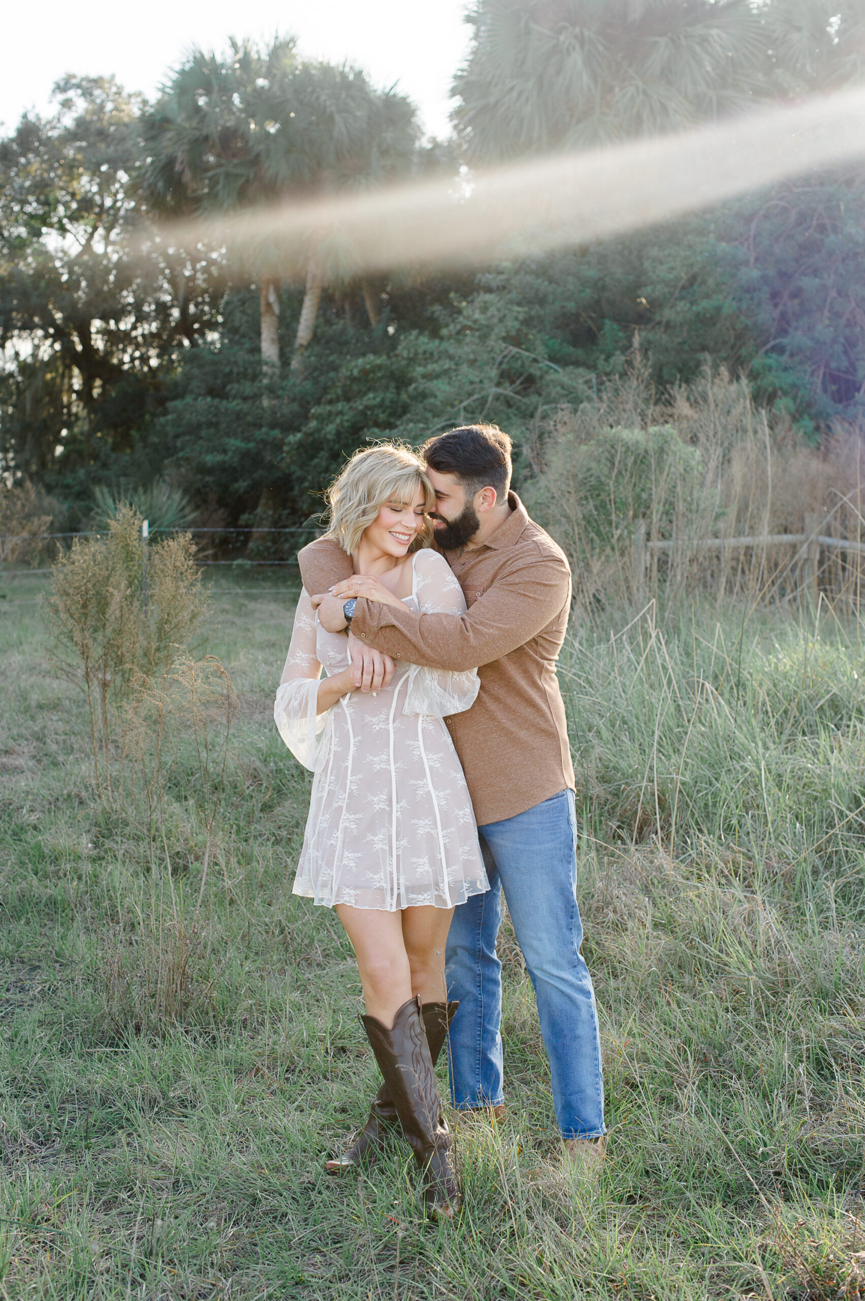 Couple standing close and cuddly during their Orlando engagement session in a tall grass field
