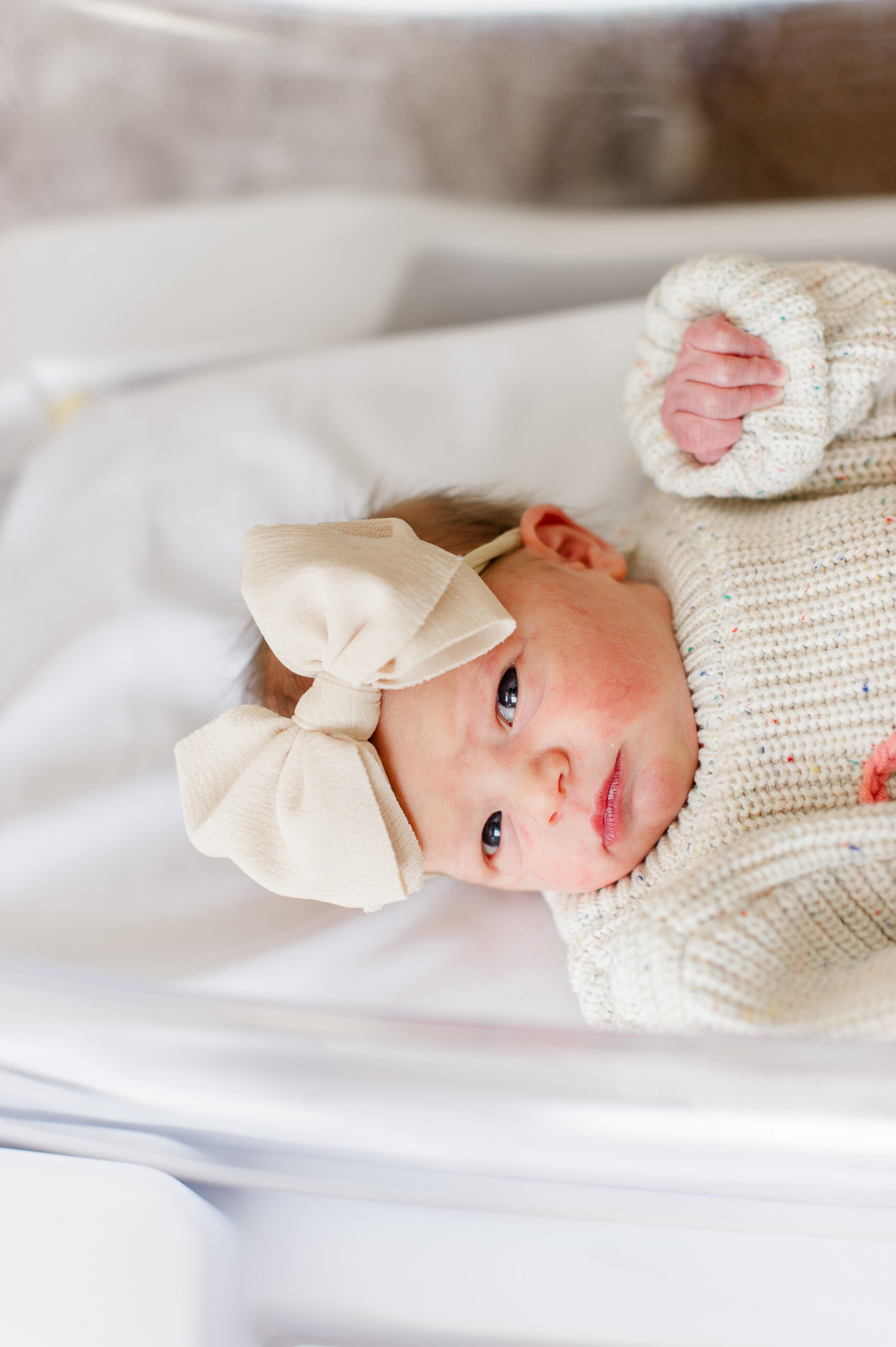 Newborn baby girl opens her eyes during her Fresh 48 session at the hospital hours after birth.