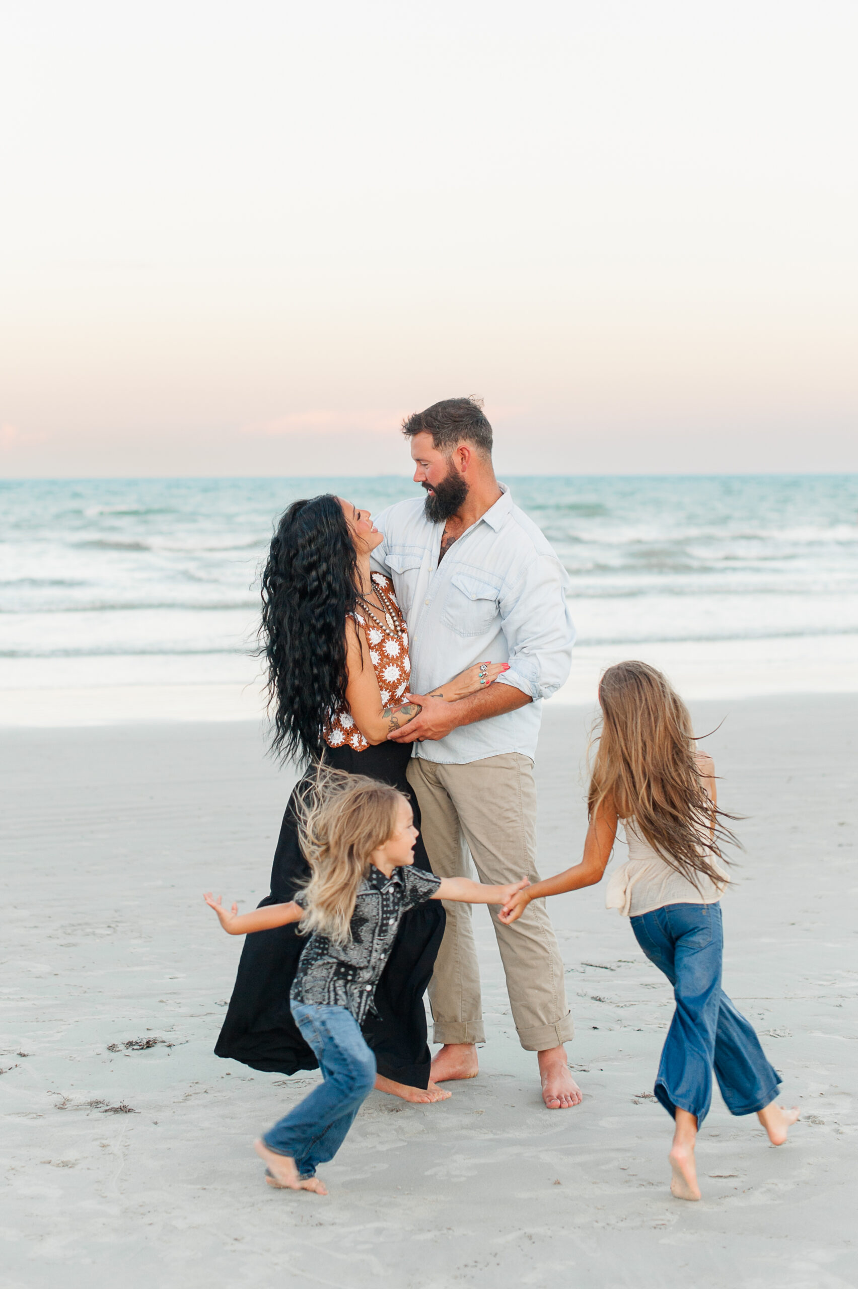 Kids playing on the beach with parents during a family session at Jetty Park.