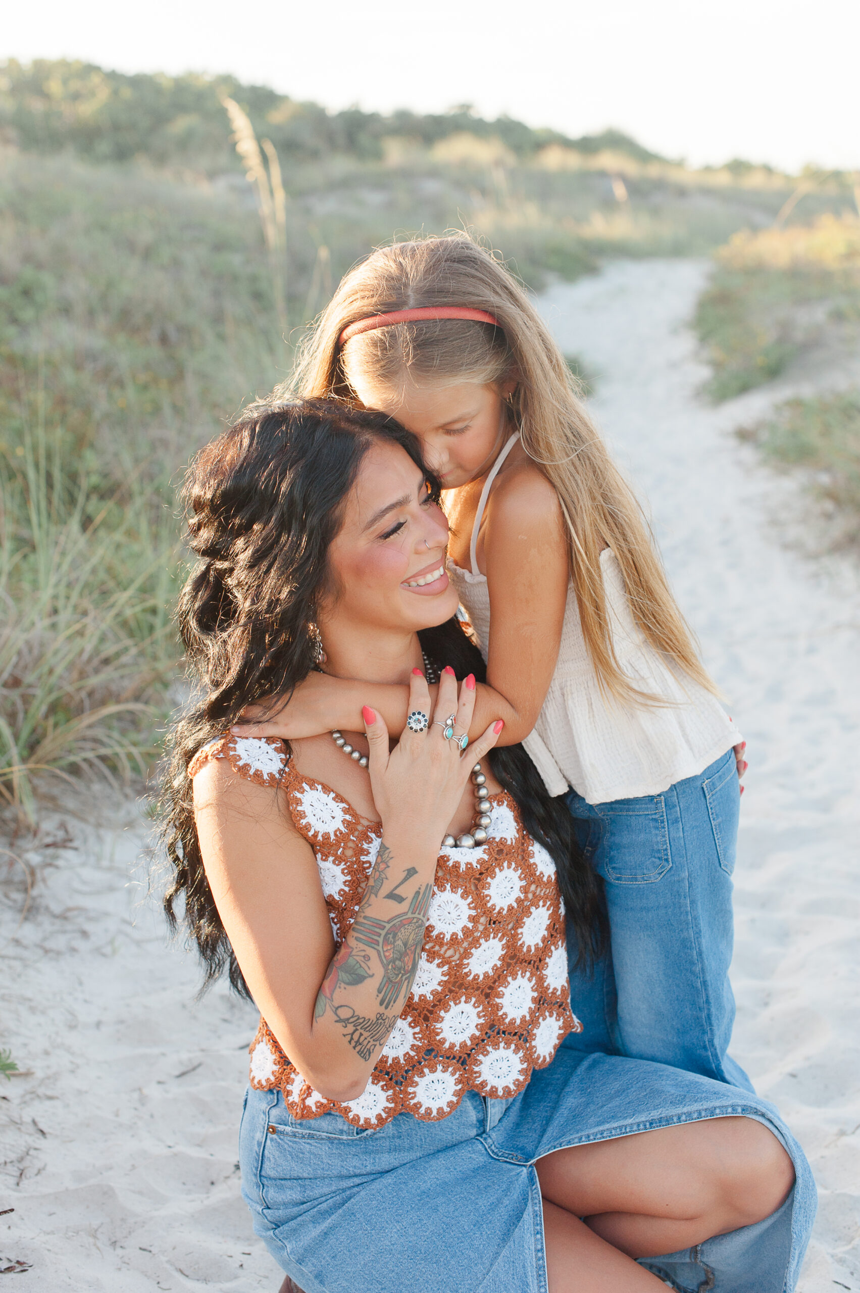 Mom and daughter expressing their love for each other during their family session near the dunes at sunset.